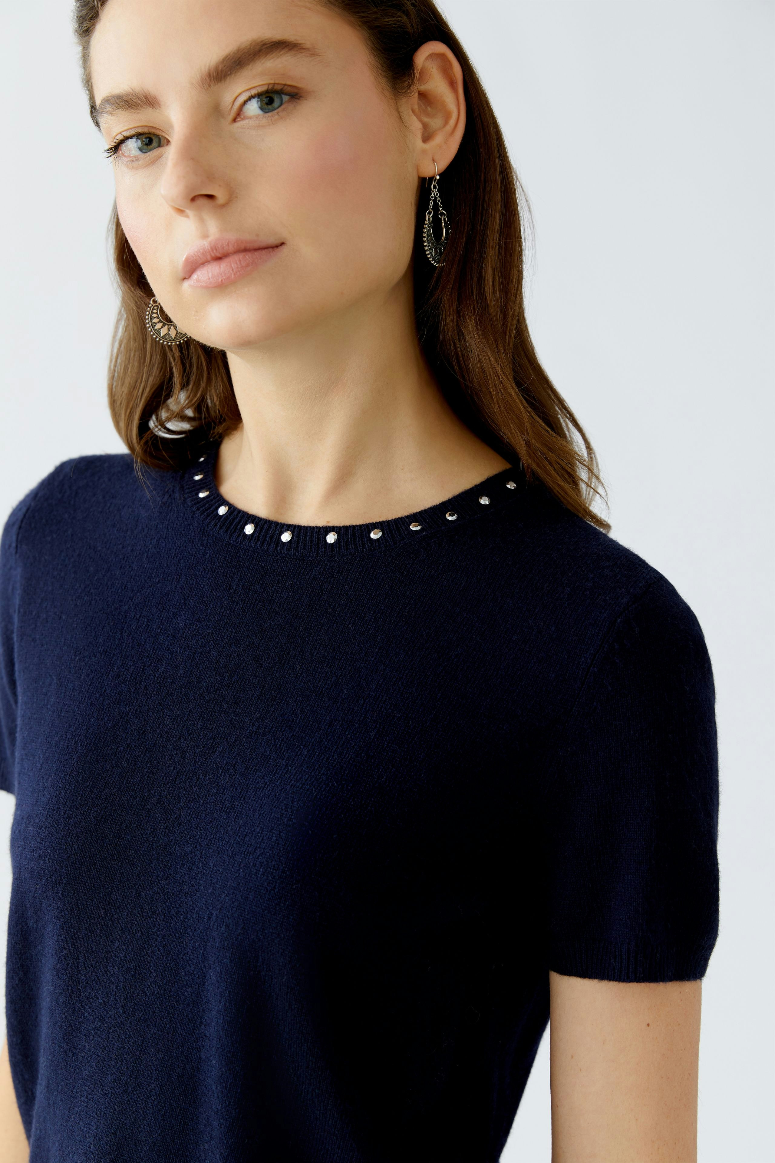 Modern women's pullover: Woman in navy pullover with decorative neckline, looking confidently at the camera.