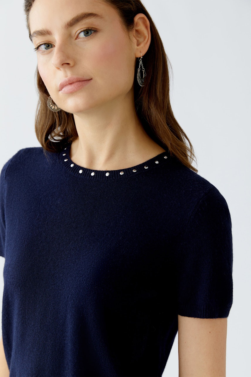 Modern women's pullover: Woman in navy pullover with decorative neckline, looking confidently at the camera.