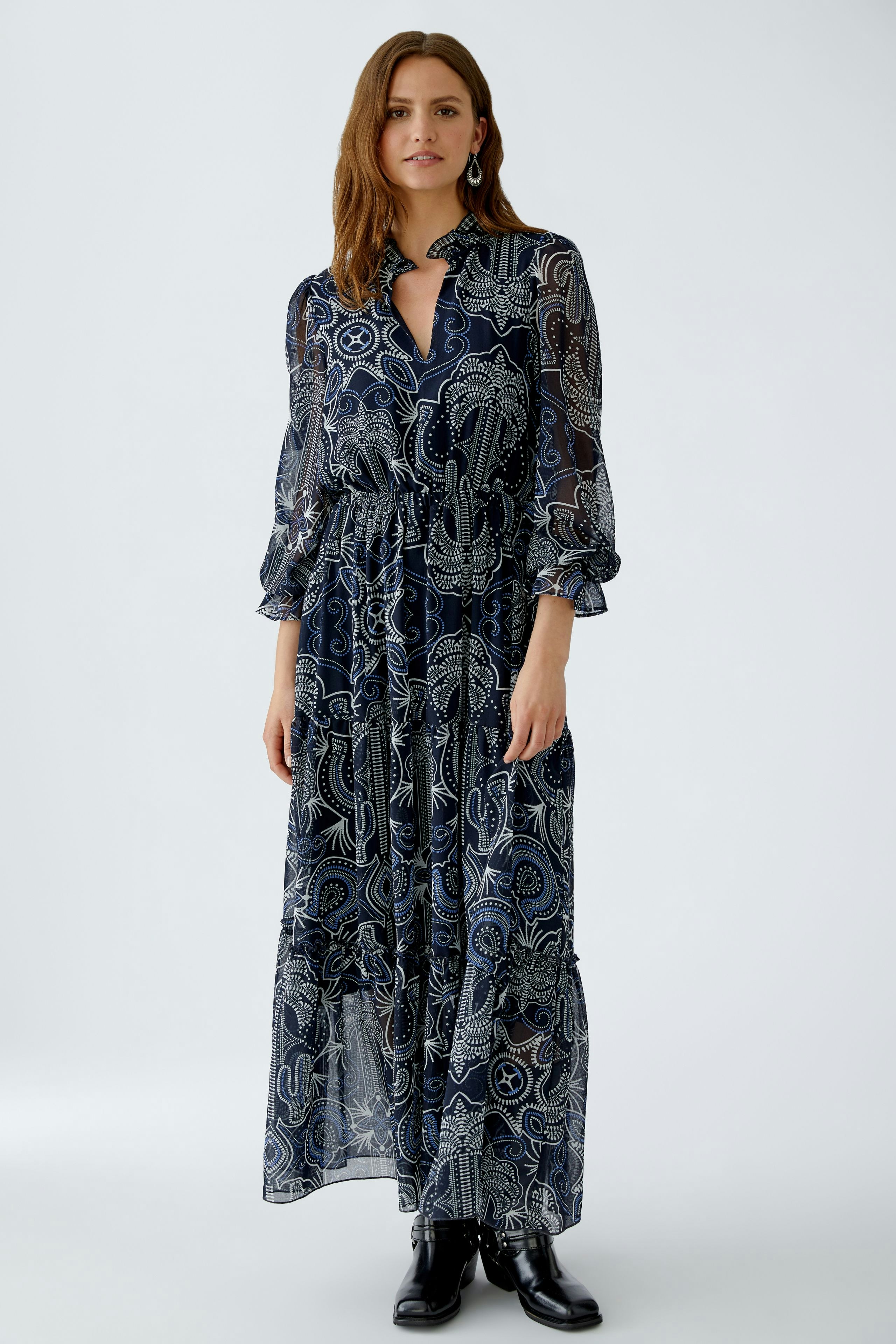 Flowy maxi dress: Woman in a navy patterned dress with long sleeves and a relaxed fit.