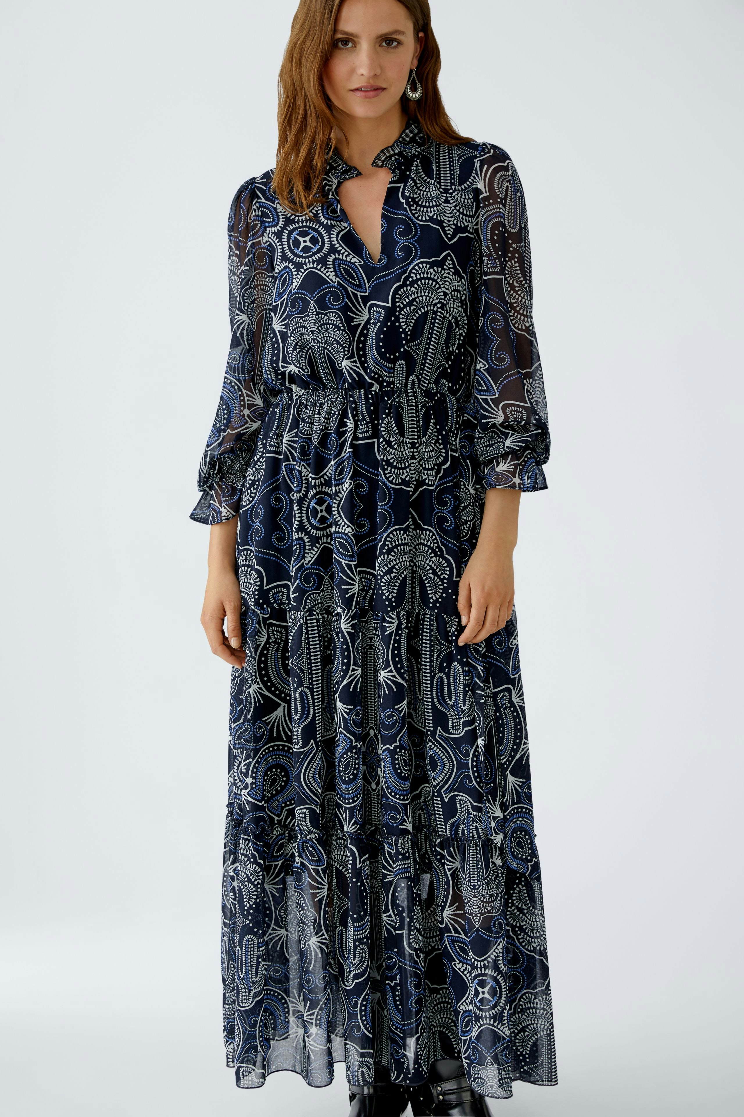 Maxi dress: Woman in a long, patterned dress with a collar and flowing sleeves.