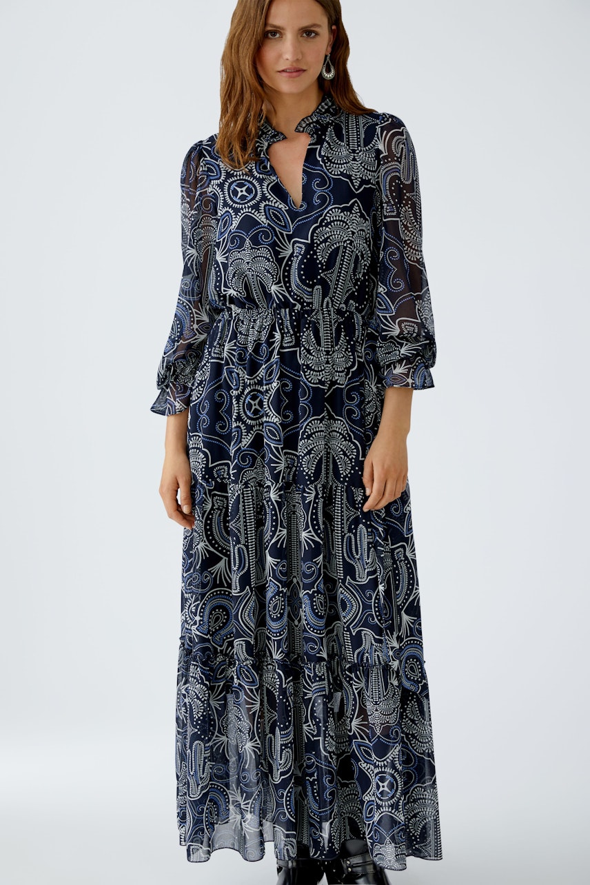 Maxi dress: Woman in a long, patterned dress with a collar and flowing sleeves.