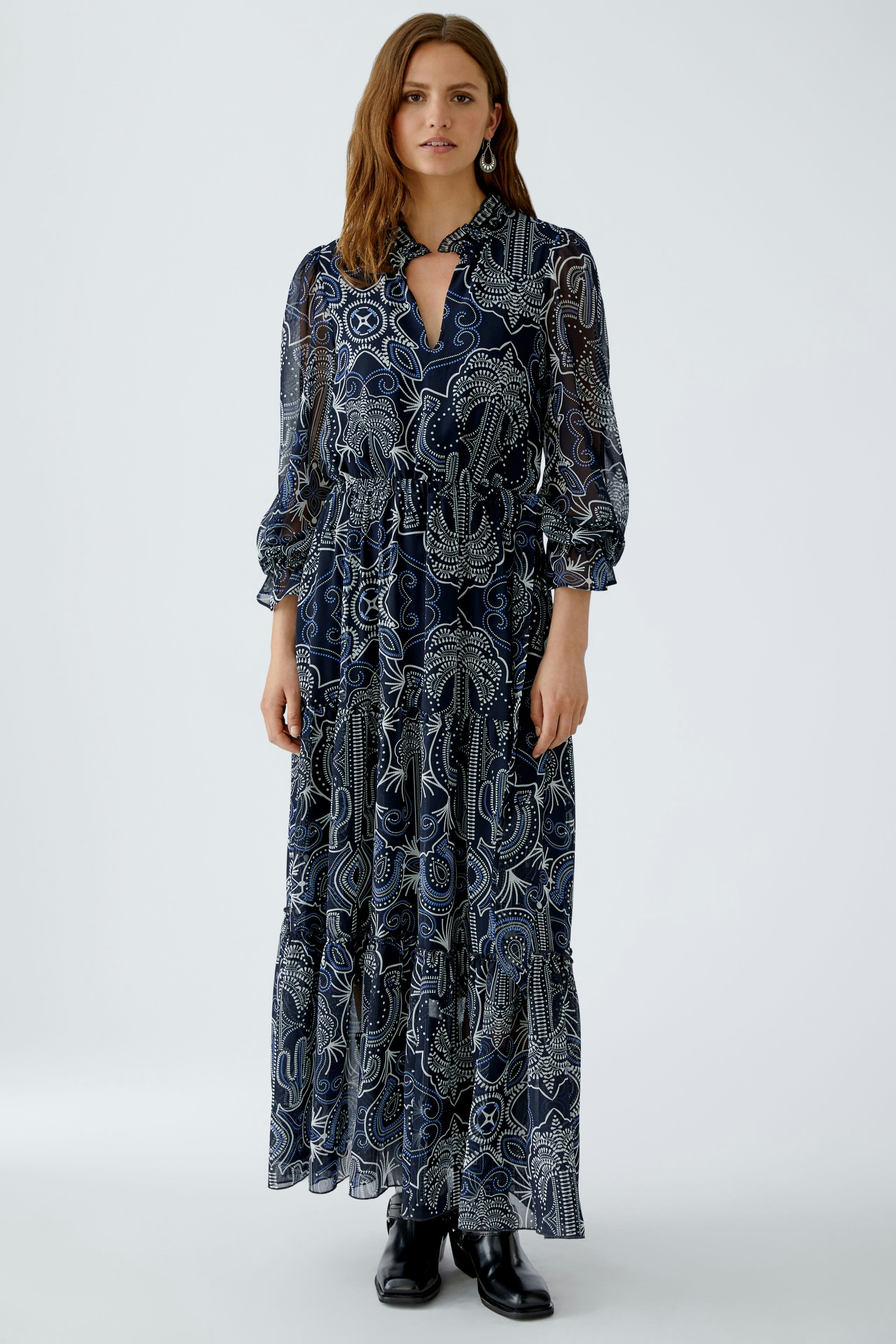 Maxi dress: Woman in a flowing navy dress with a floral pattern and long sleeves, standing confidently.