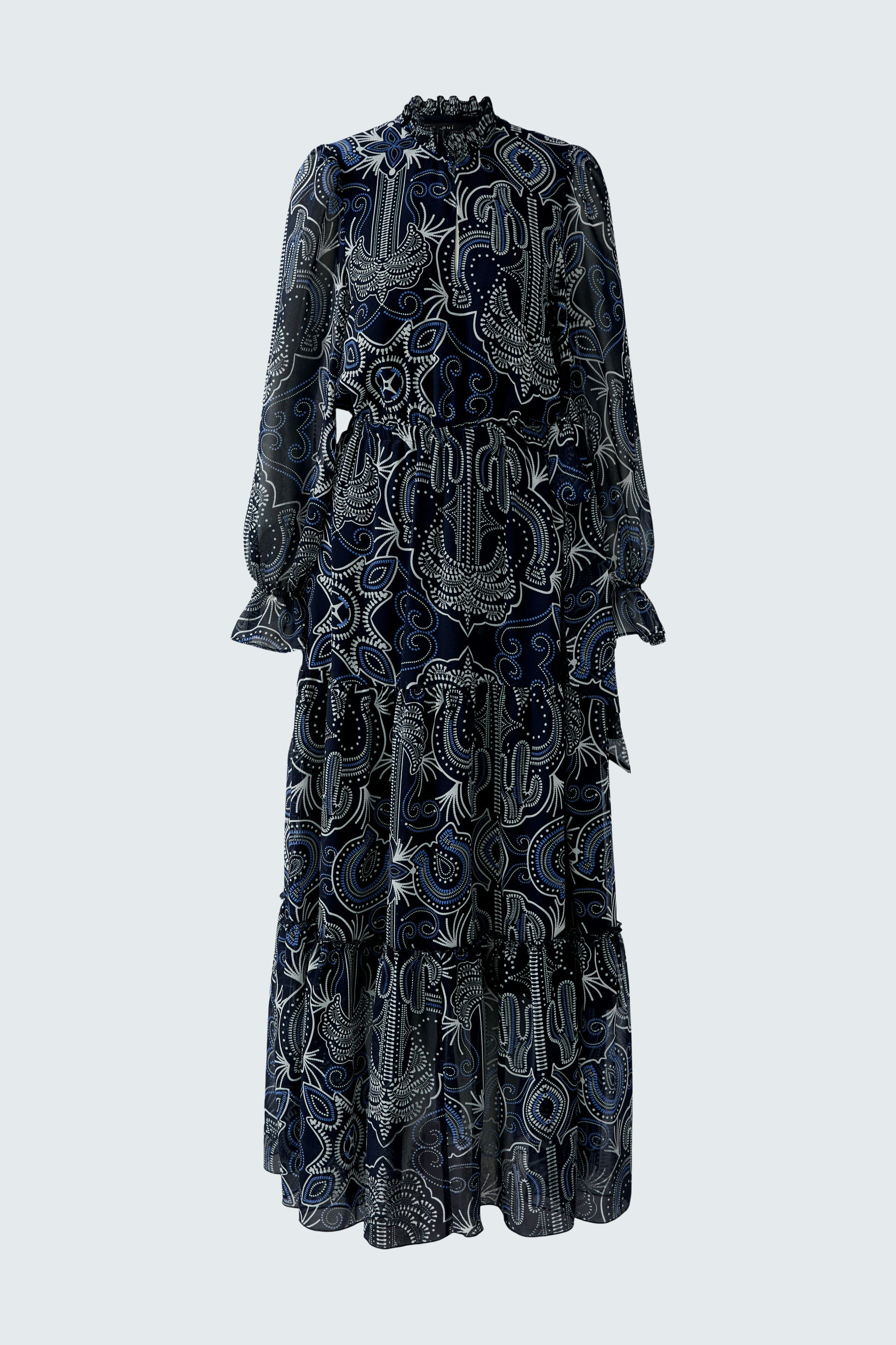 Maxi dress: A woman in a flowing, patterned maxi dress with long sleeves and a high neckline.