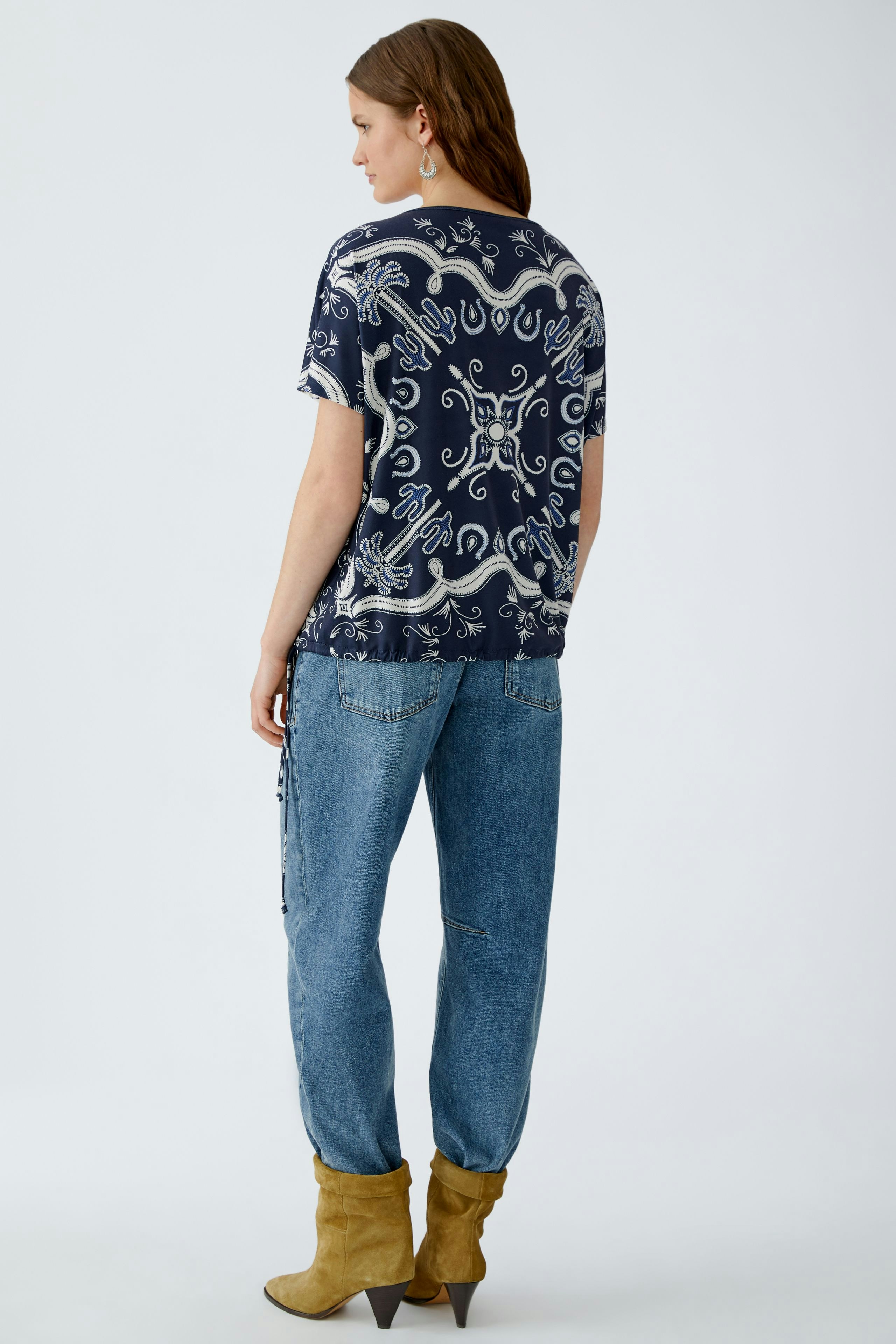 Casual women's T-shirt: A woman in a navy patterned tee paired with relaxed jeans.