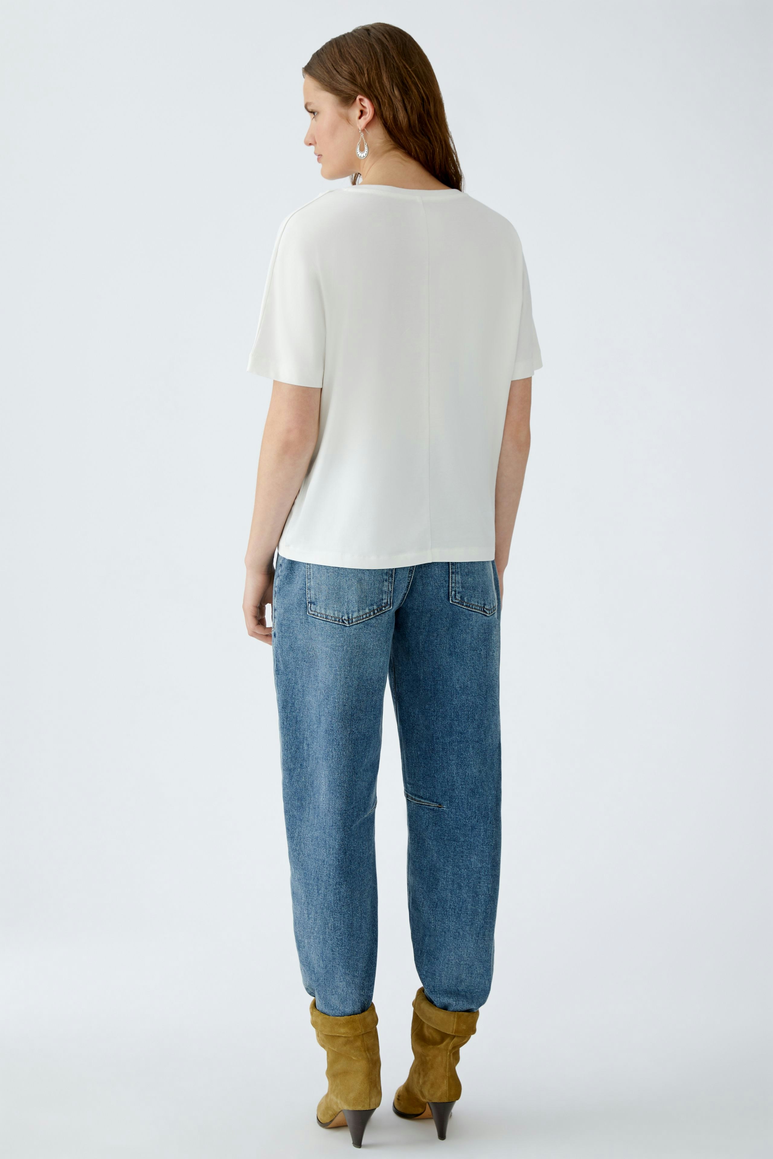 Damen-T-Shirt: Frau trägt ein schlichtes, weißes T-Shirt mit kurzen Ärmeln und lässigen Jeans.