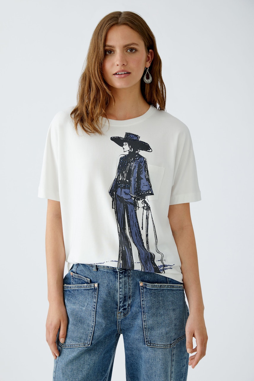 Casual women's T-shirt: Young woman in a white tee featuring a graphic print, paired with relaxed jeans.