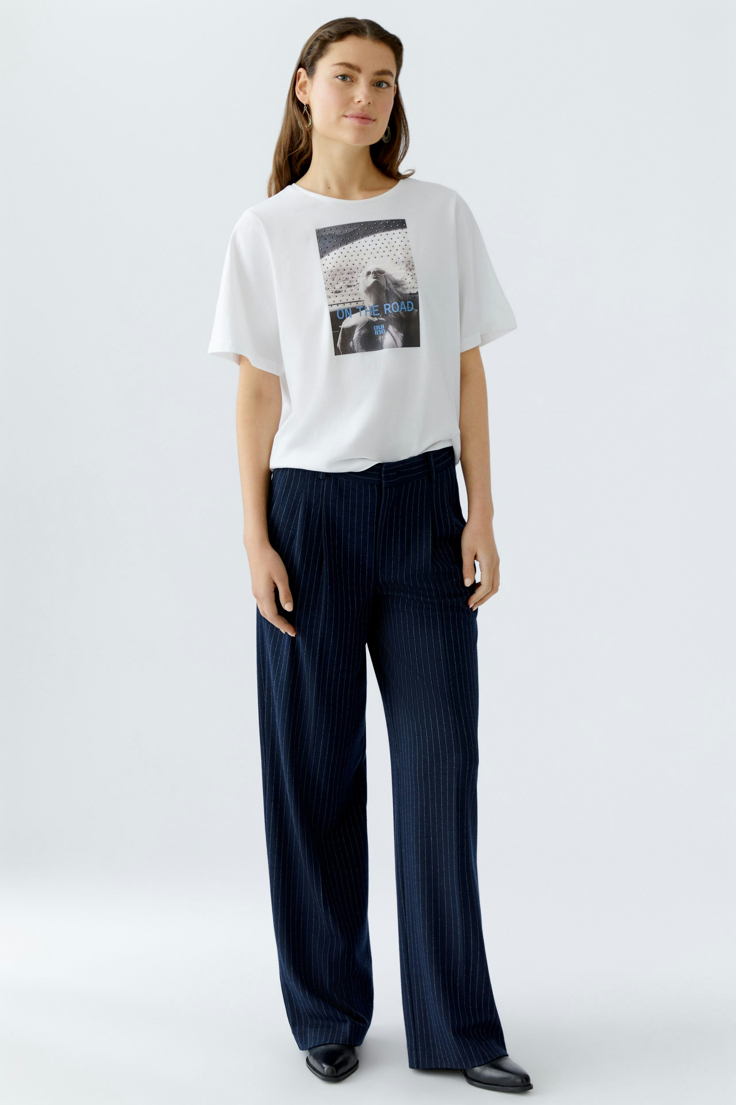 Casual women's T-shirt: A woman in a white tee with a graphic print, paired with wide-leg pants.