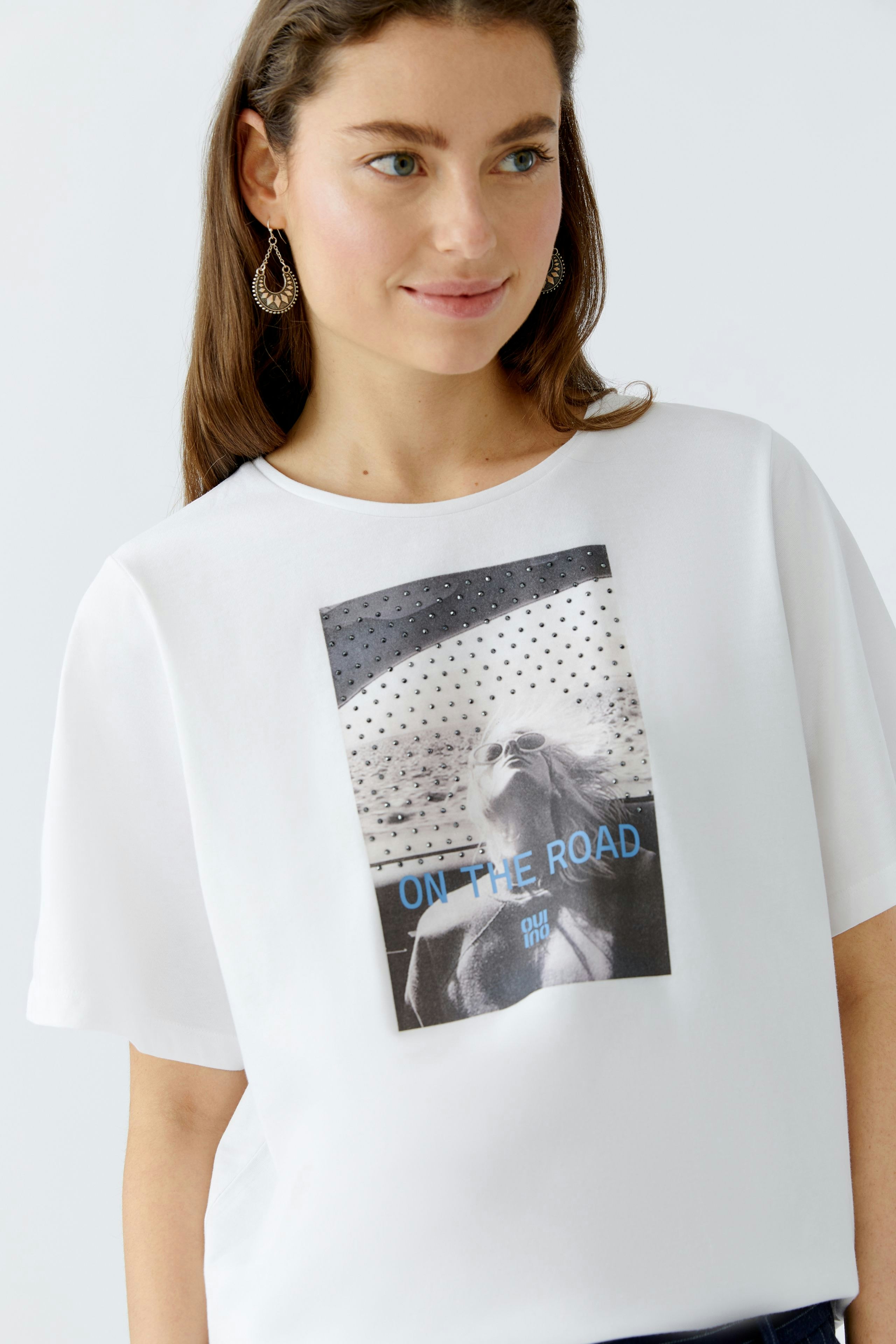 Casual women's T-shirt: Young woman in a white tee with a graphic print, smiling confidently.