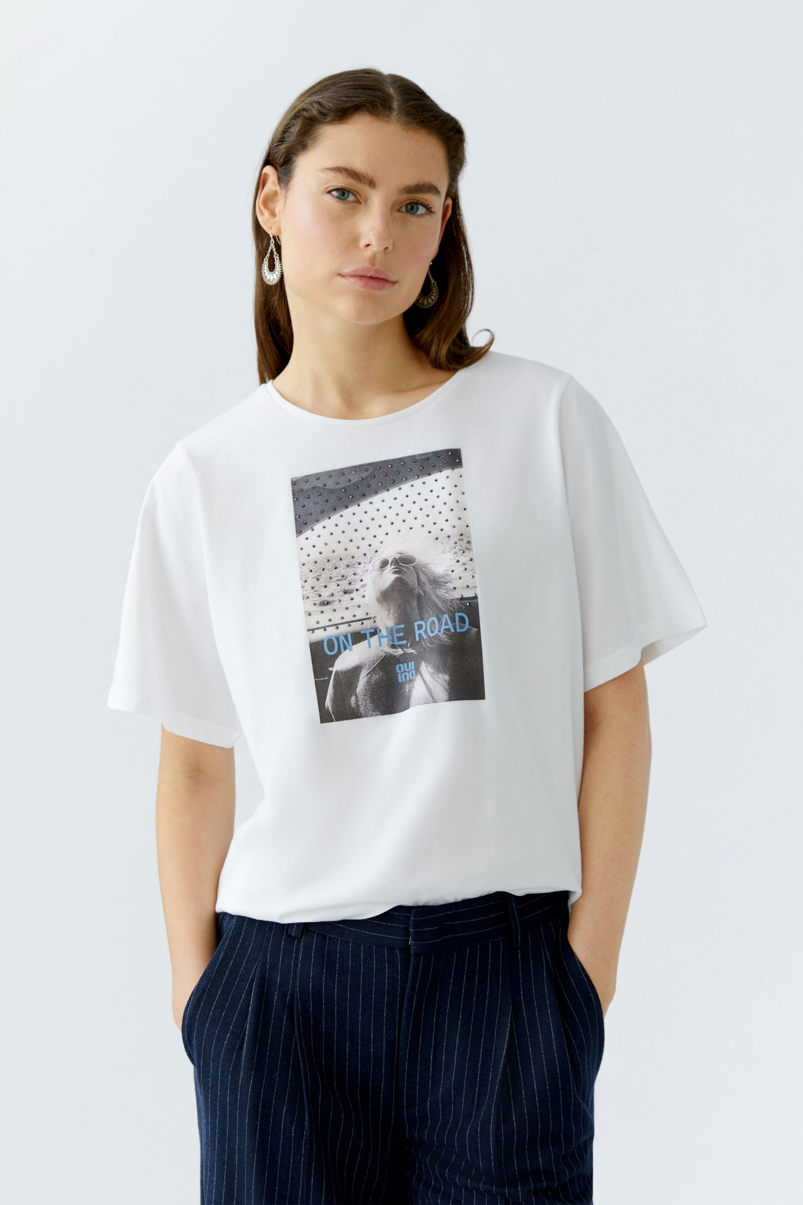 Casual women's T-shirt: A woman in a white tee with a graphic print, paired with navy striped pants.
