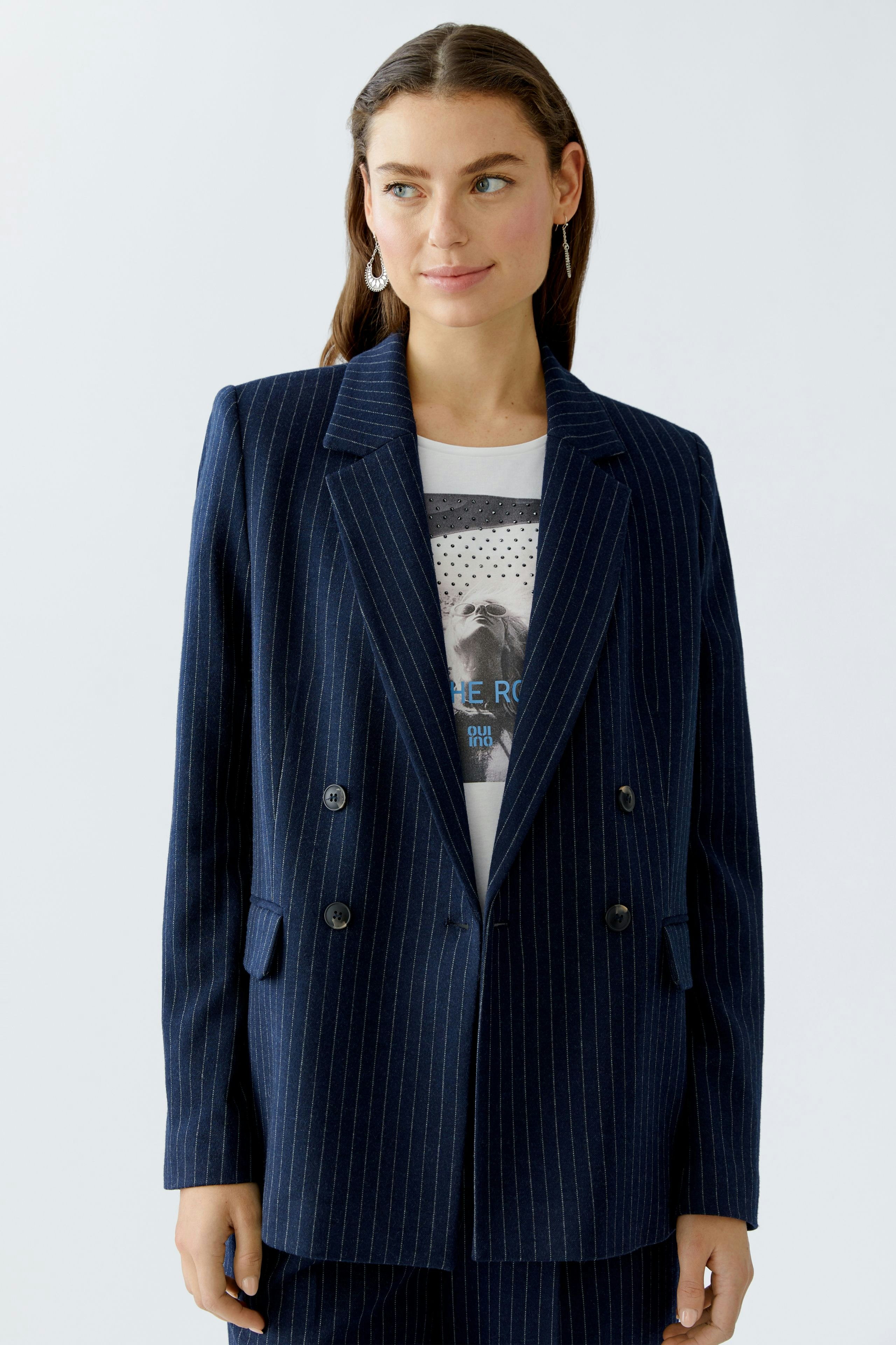 Modern women's blazer: A woman in a navy pinstriped blazer over a graphic tee, looking confident.