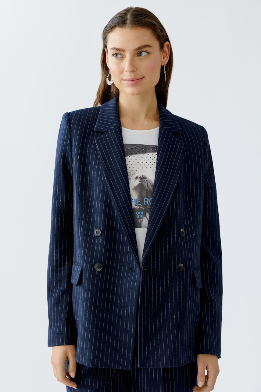 Modern women's blazer: A woman in a navy pinstriped blazer over a graphic tee, looking confident.