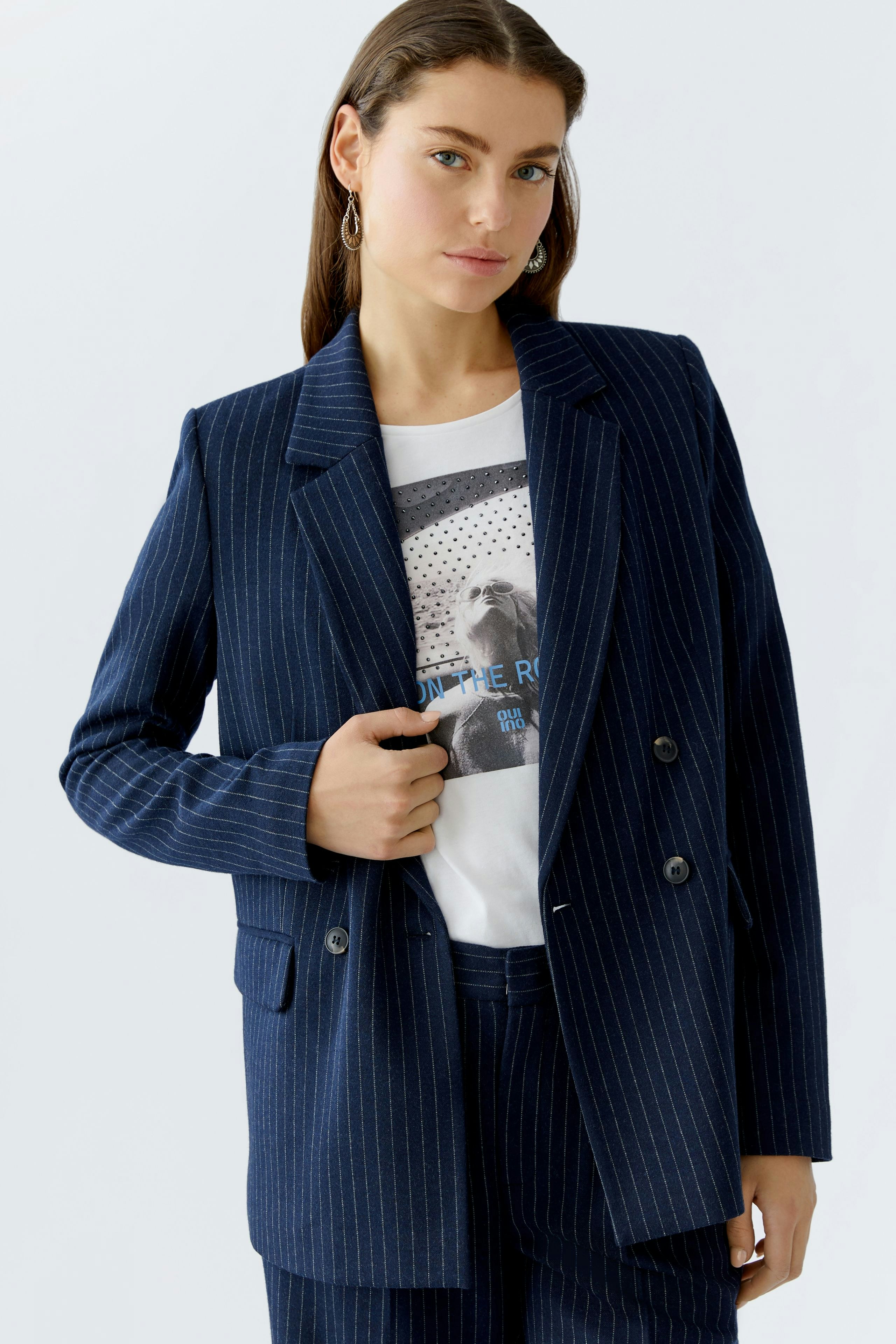 Stylish women's blazer: A woman in a navy pinstriped blazer over a graphic tee.