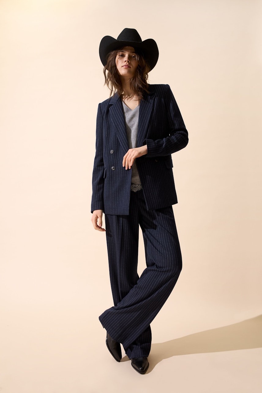 Stylish women's blazer: A woman in a navy pinstripe blazer paired with wide-leg pants and a cowboy hat.