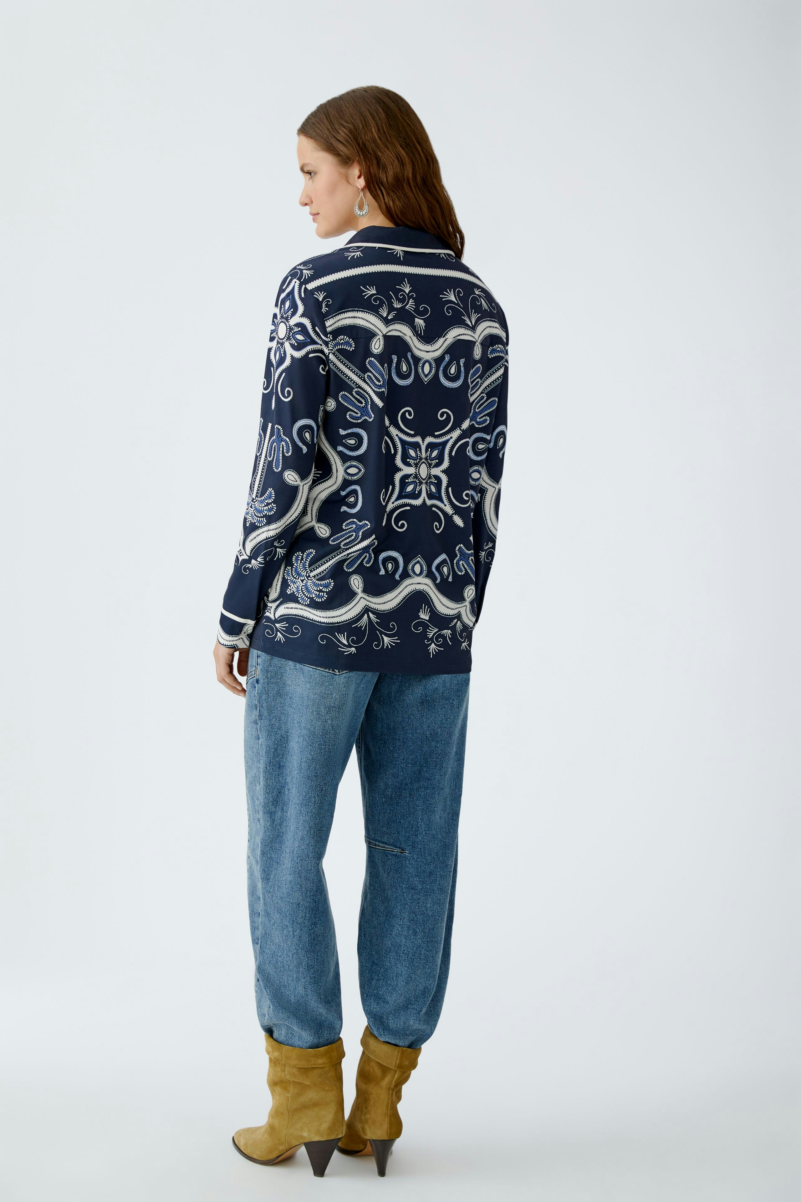 Stylish women's blouse: A woman in a navy patterned blouse paired with relaxed denim pants.