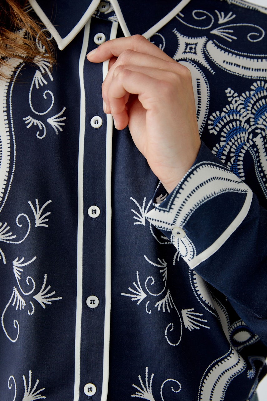 Damen-Bluse: Frau in navyfarbener Bluse mit floralem Muster und Knopfleiste.
