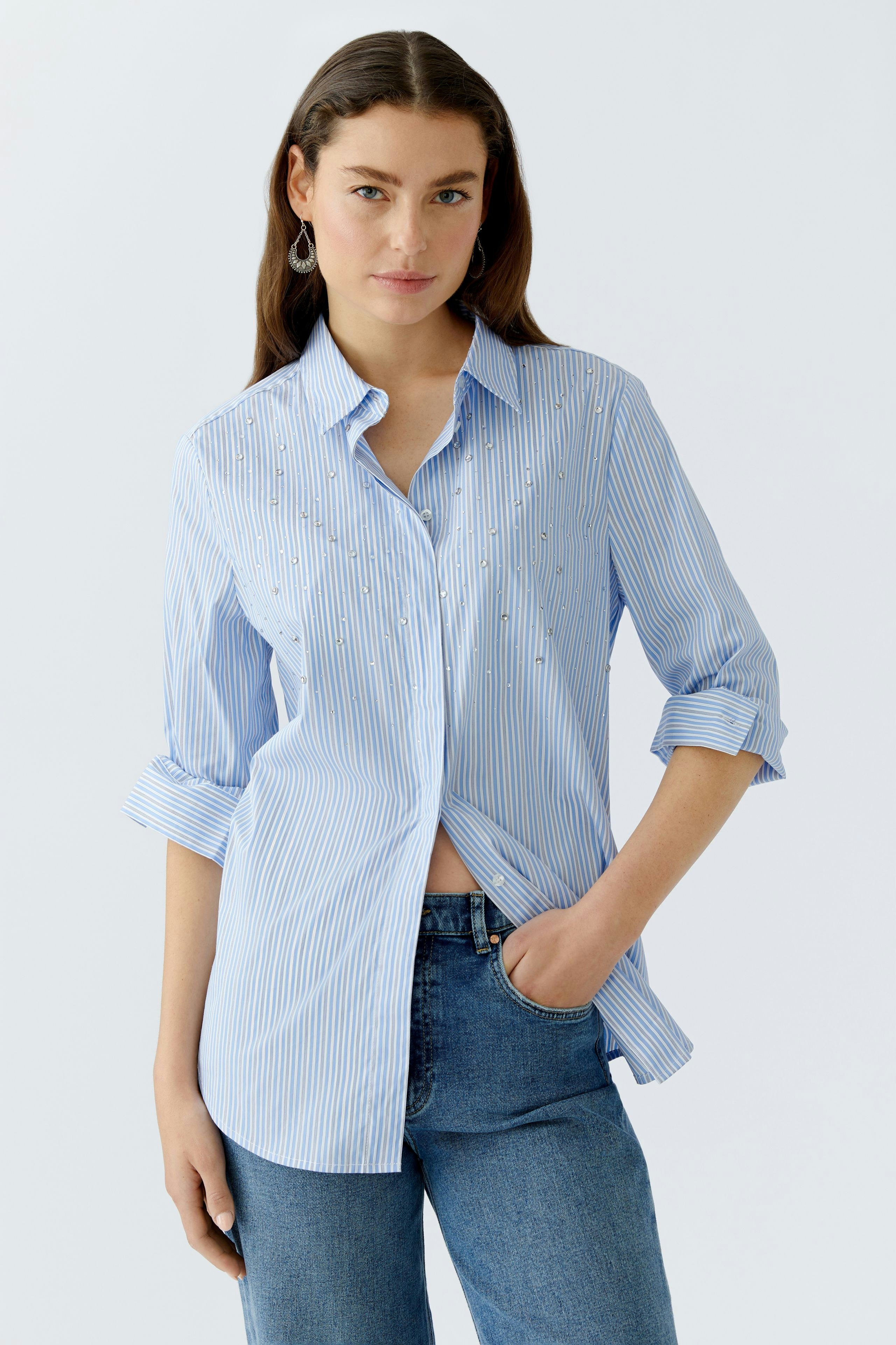 Casual women's blouse: Young woman in a light blue striped blouse with rolled-up sleeves.