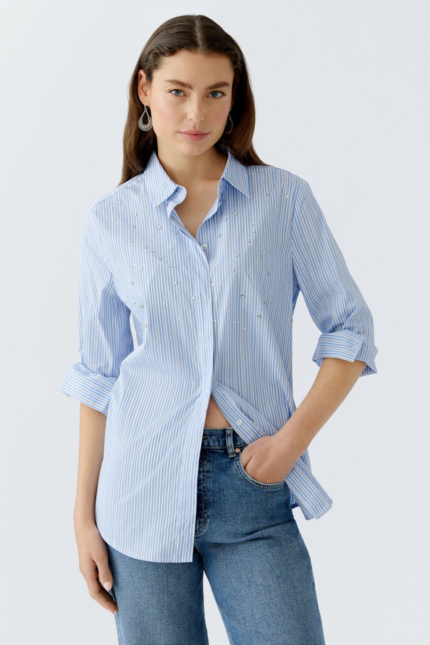 Casual women's blouse: Young woman in a light blue striped blouse with rolled-up sleeves.