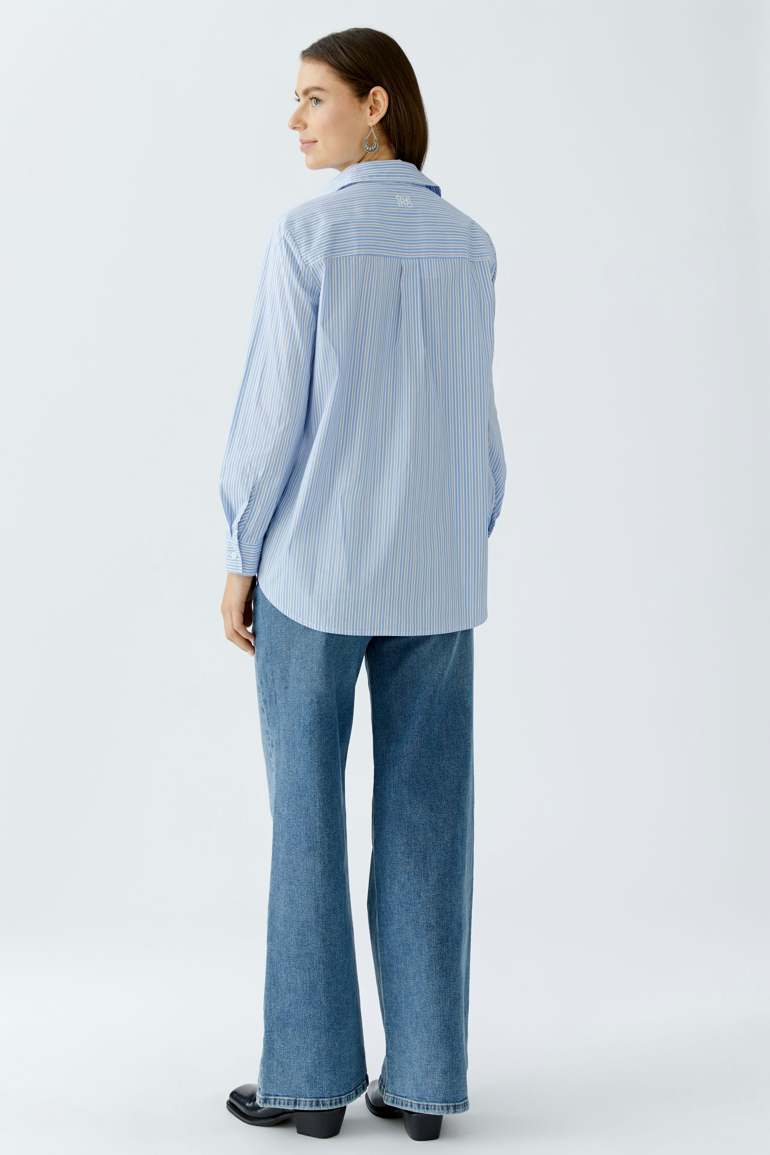Casual women's blouse: Woman in a light blue striped blouse with a relaxed fit and long sleeves.