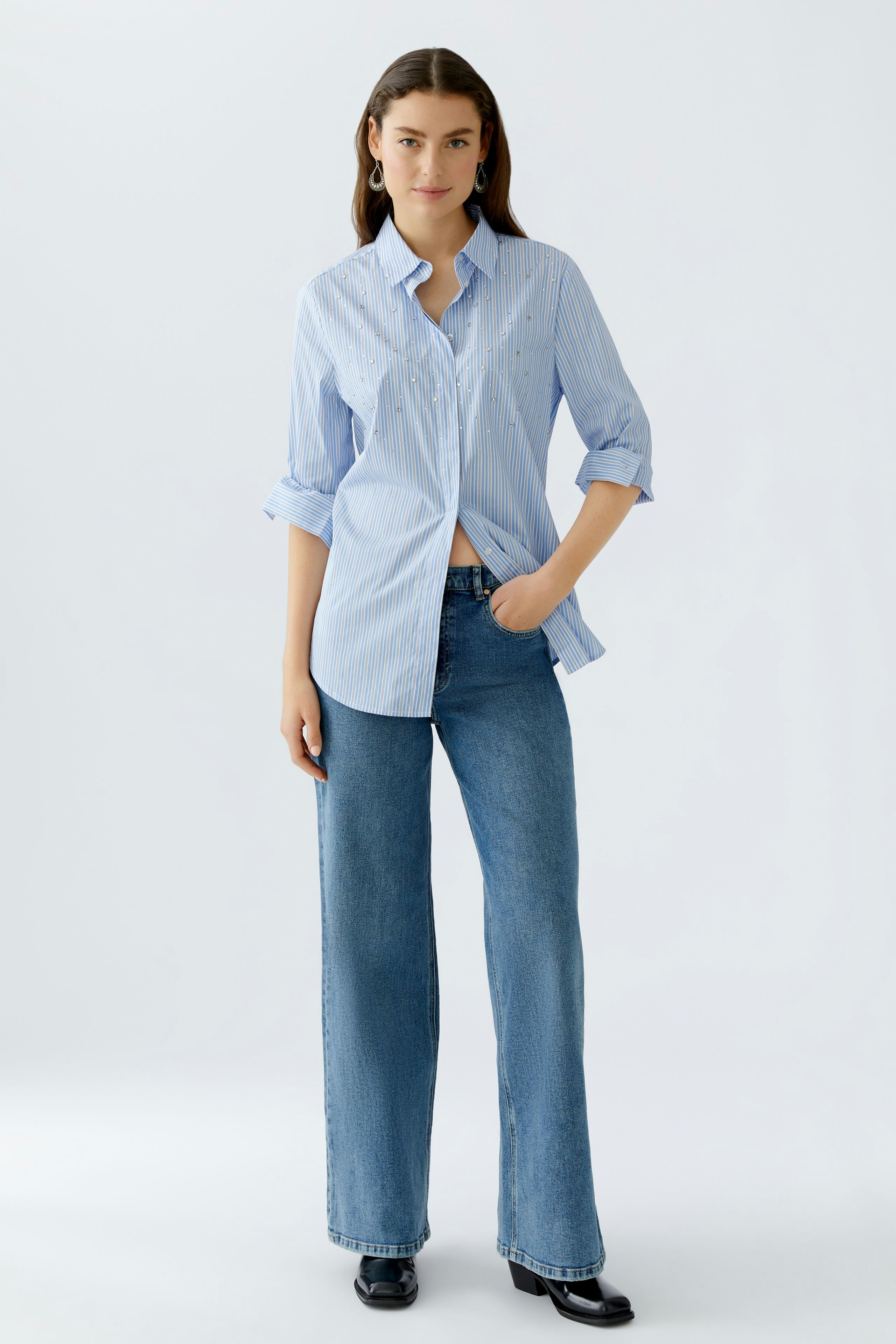 Casual women's blouse: A woman in a light blue striped blouse with rolled sleeves and relaxed fit.