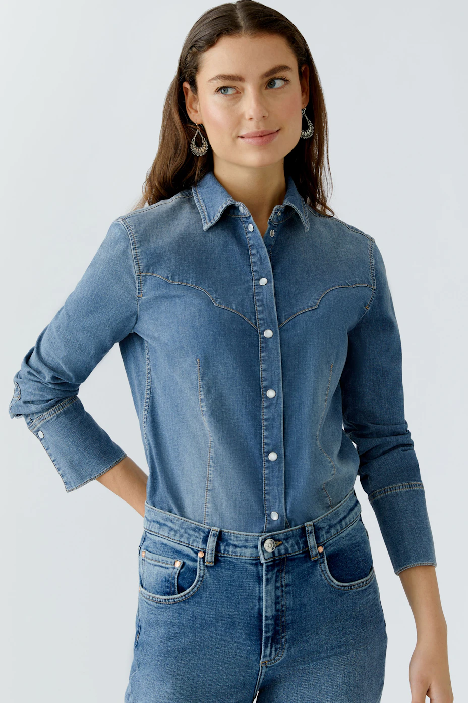 Casual women's denim shirt: A woman in a blue denim shirt with button closure and long sleeves.