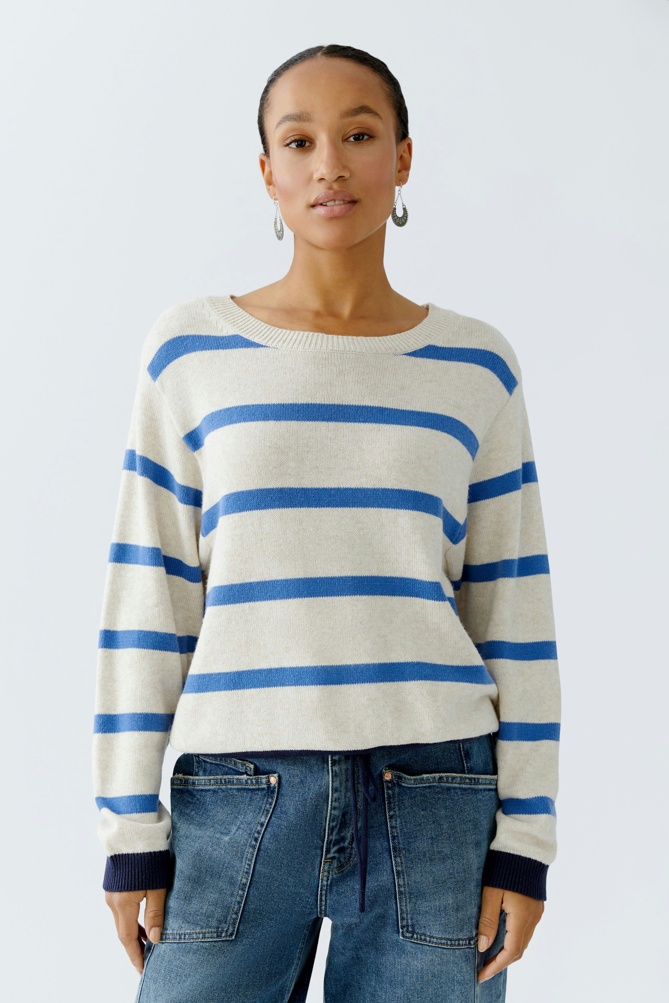 Casual women's pullover: Young woman in a striped pullover with blue and beige colors, paired with jeans.