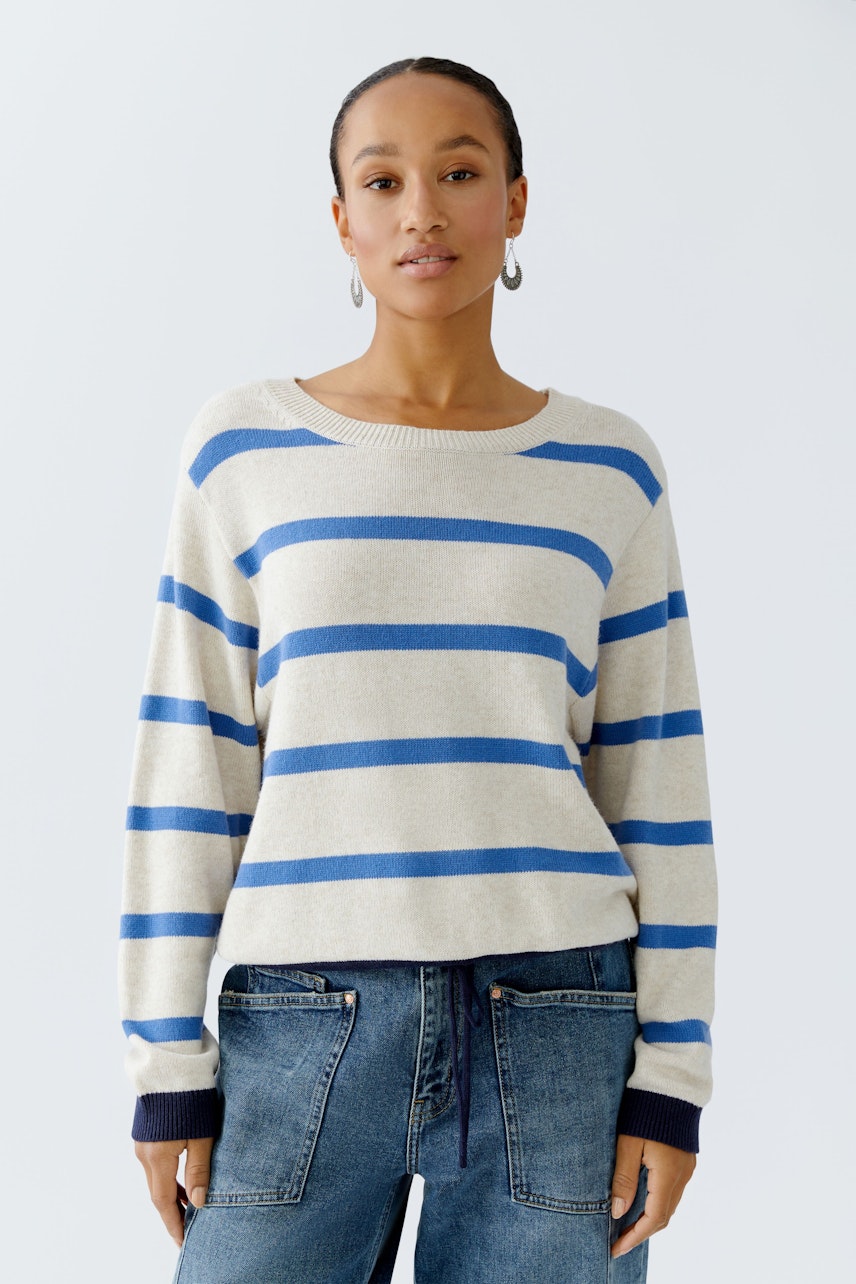 Bequemer Damen-Pullover: Frau trägt einen gestreiften Pullover in Beige und Blau, kombiniert mit Jeans.