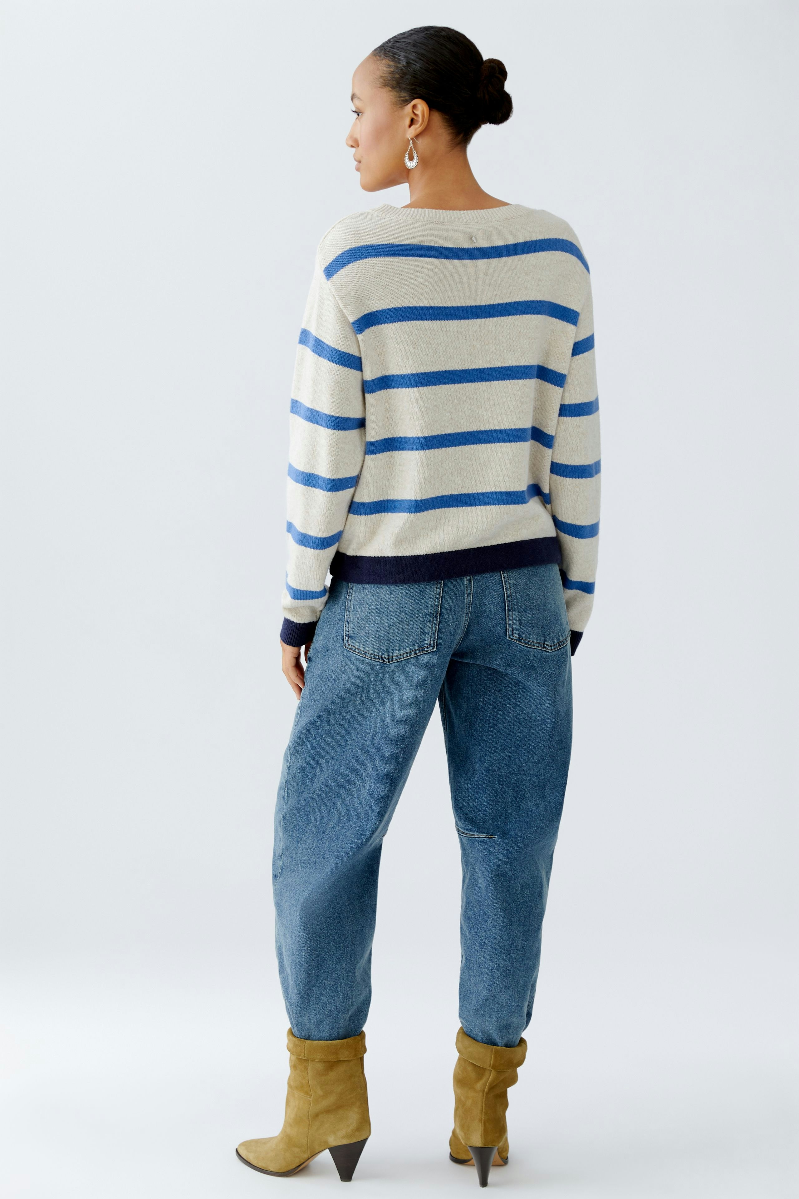 Casual women's pullover: A woman in a striped pullover with blue and beige colors, paired with relaxed jeans.