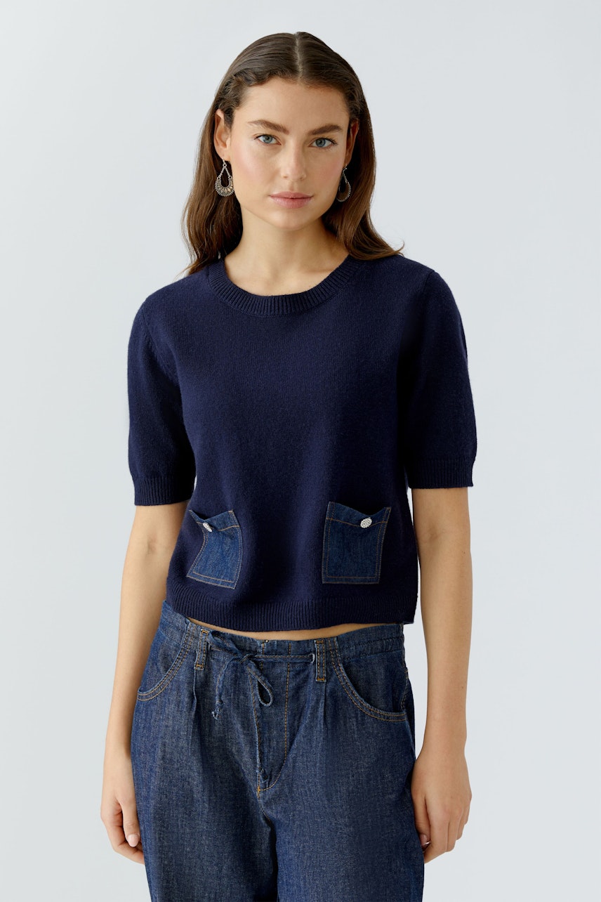 Casual women's pullover: A woman in a navy short-sleeve pullover with denim pockets.
