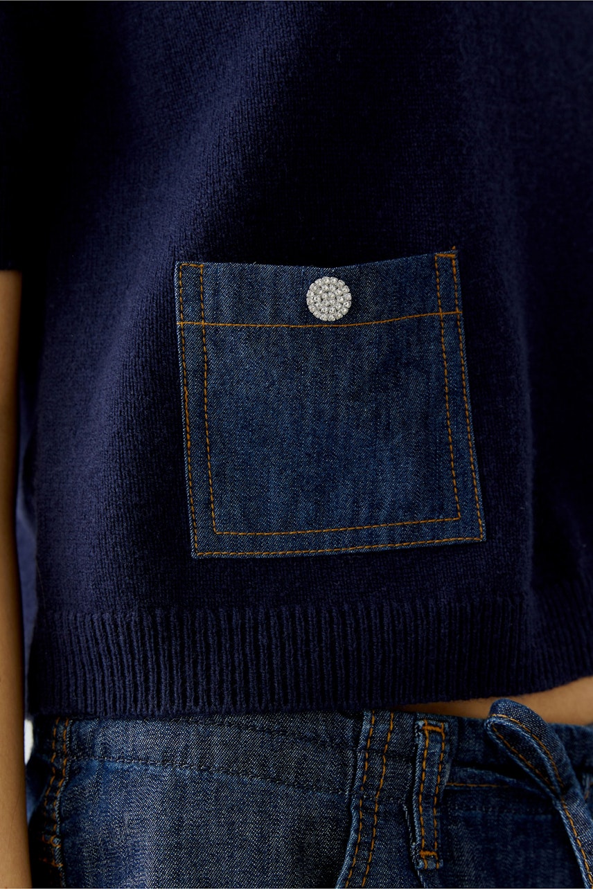 Casual women's pullover: Close-up of a navy pullover with a denim pocket detail.
