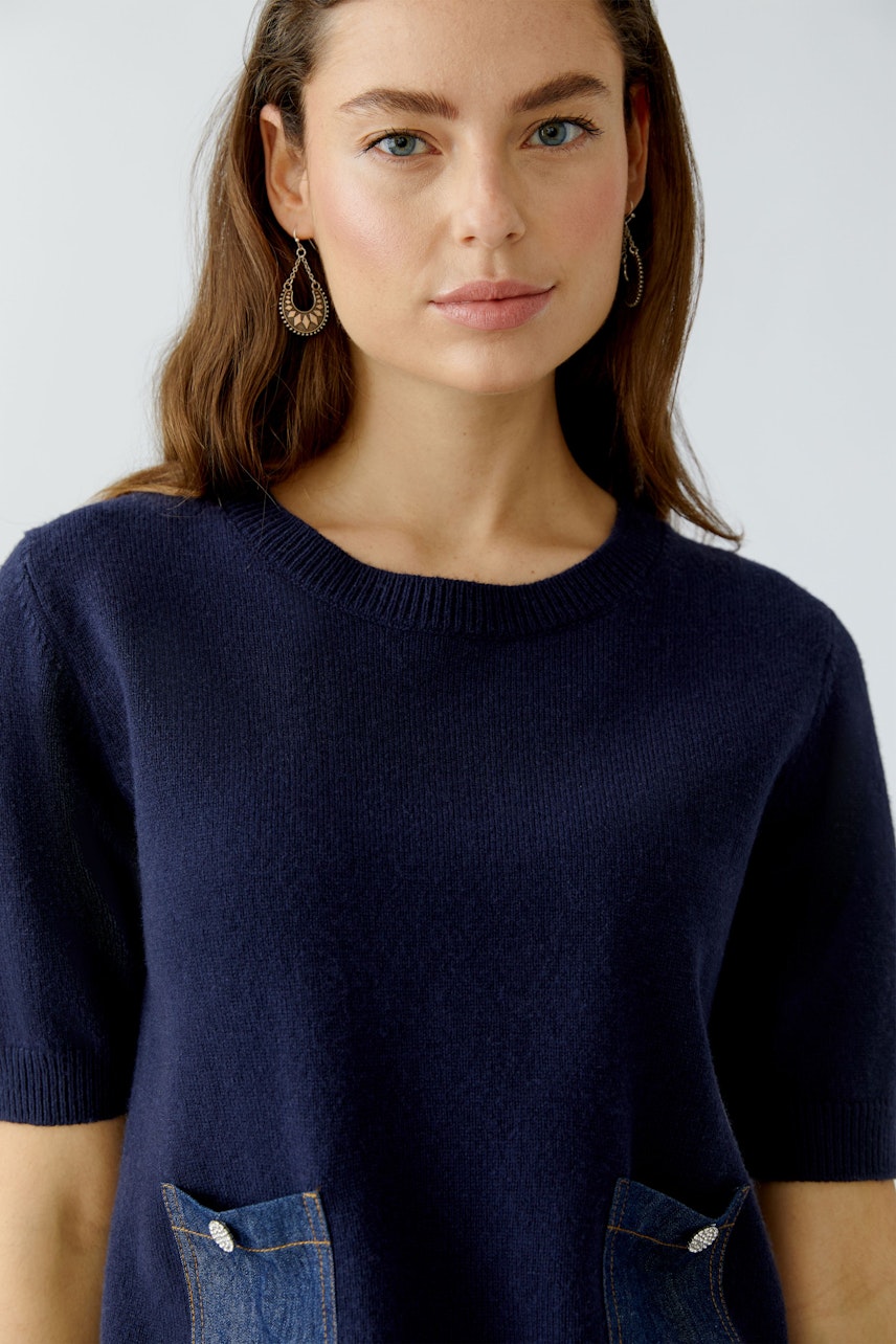 Casual women's pullover: Young woman in a navy pullover with denim pockets, looking confidently at the camera.