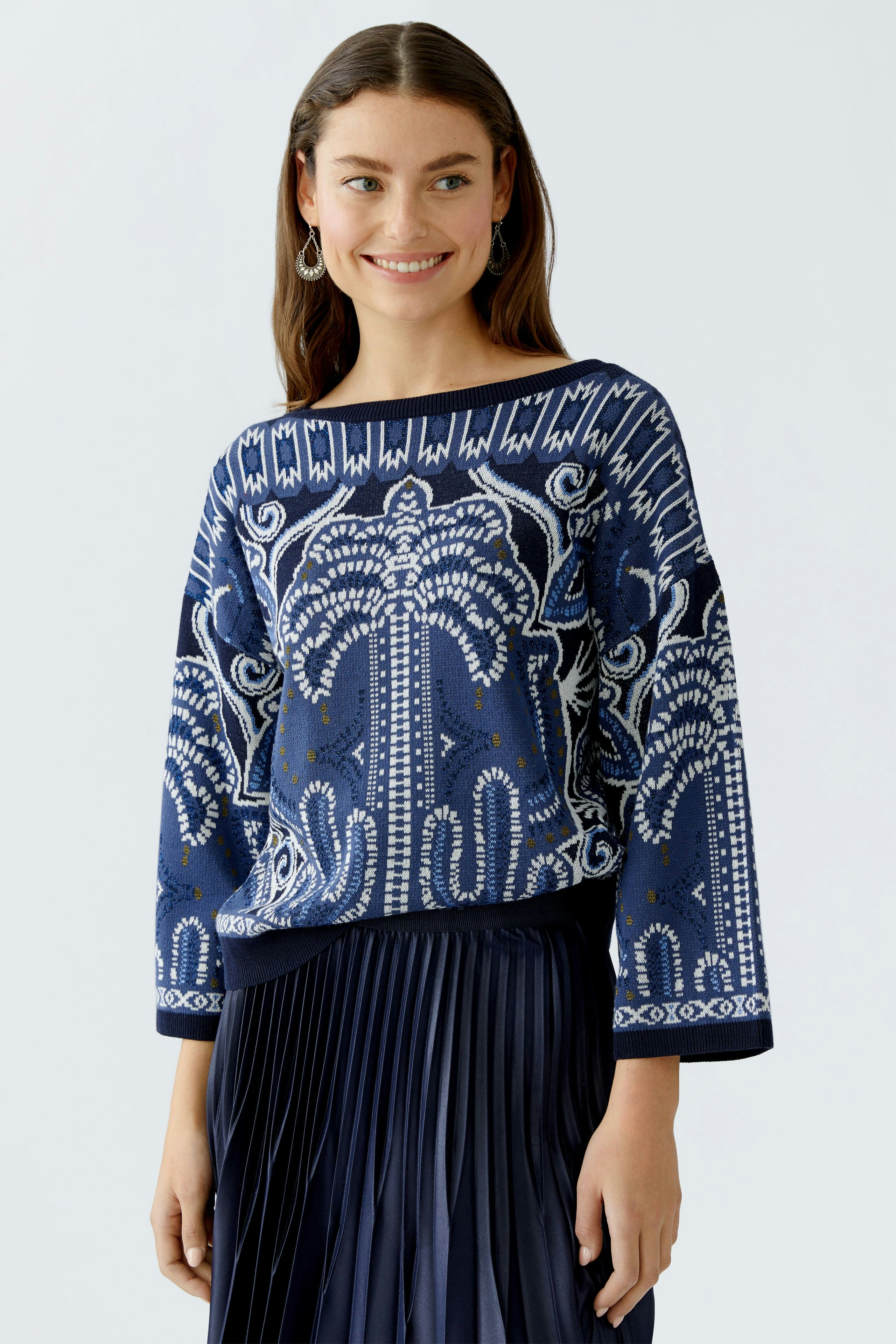 Damen-Pullover: Frau trägt einen blauen, gemusterten Pullover mit weitem Schnitt und lässigem Design.