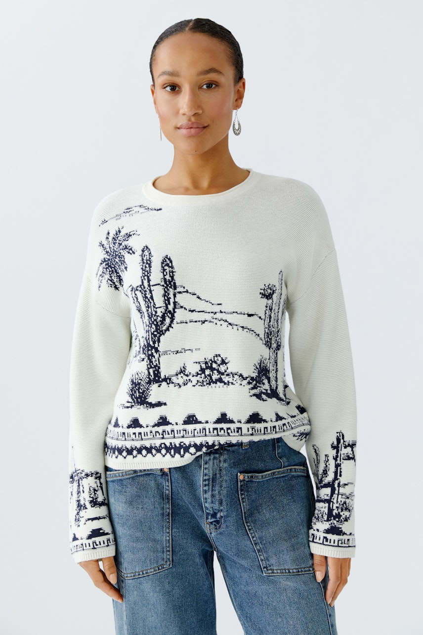 Casual women's pullover: Young woman in a light pullover with a desert landscape design and relaxed fit.