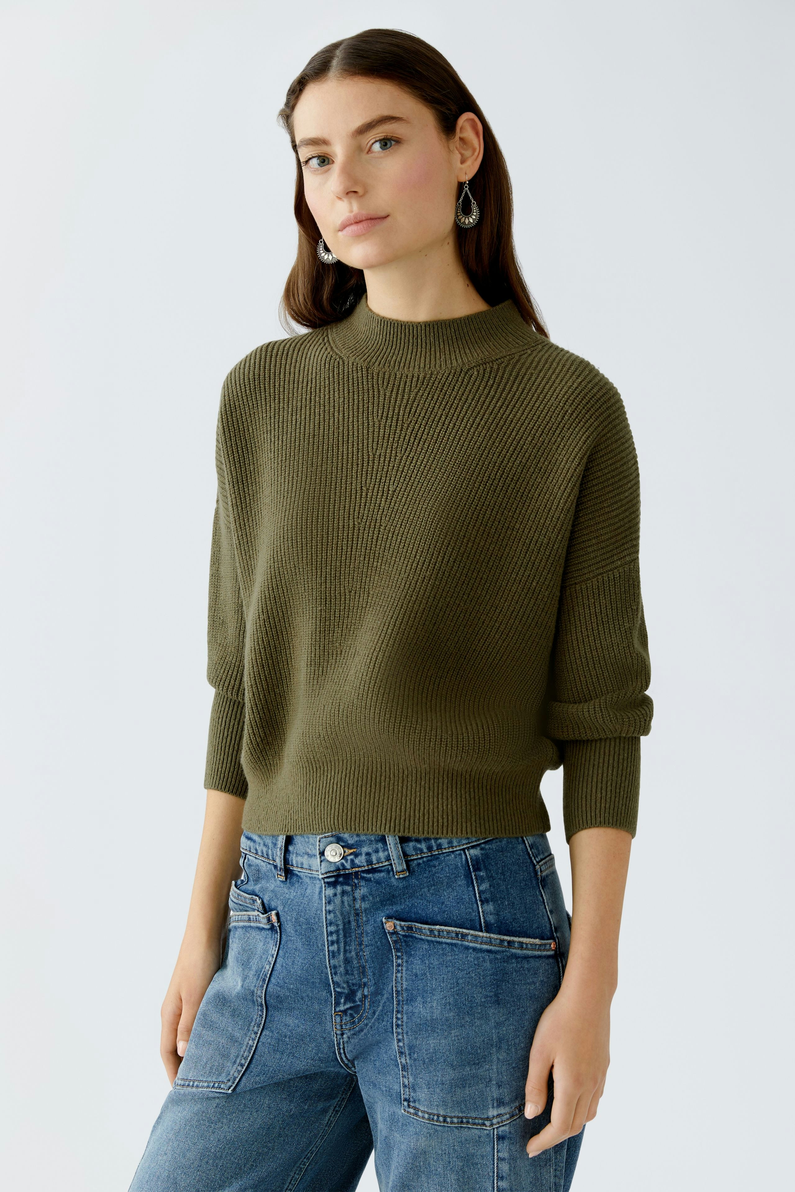Casual women's pullover: Young woman in a green ribbed pullover paired with relaxed-fit jeans.