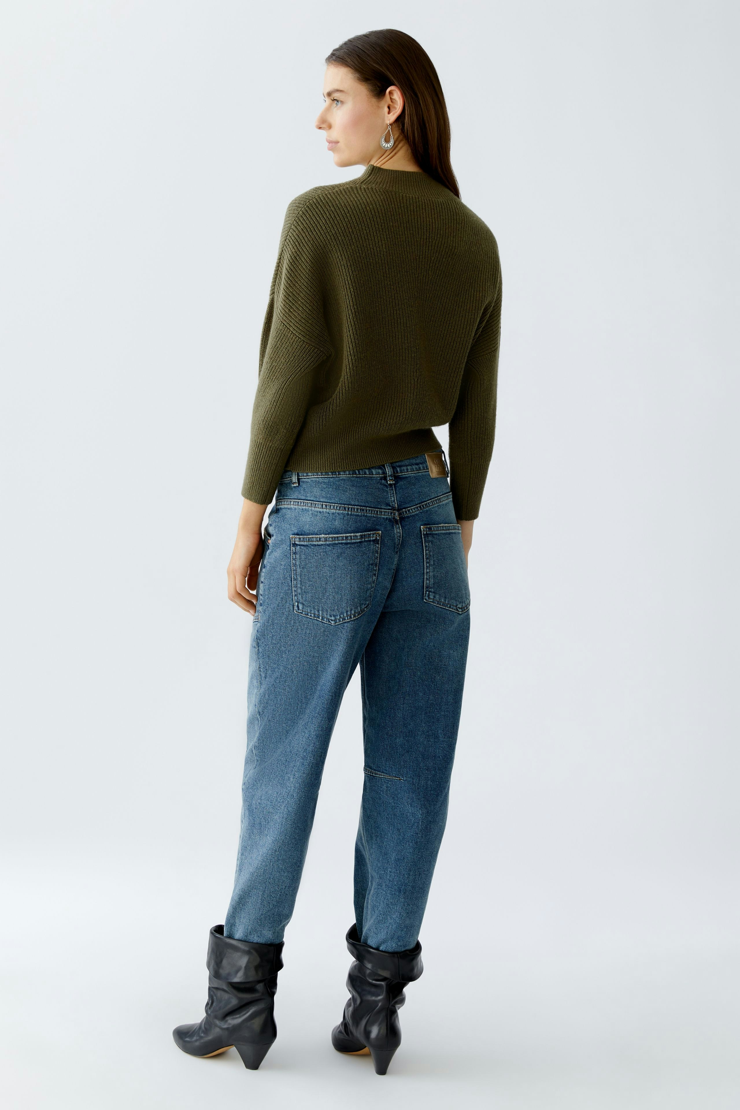 Casual women's pullover: A woman in a green pullover paired with blue jeans, showcasing a relaxed style.