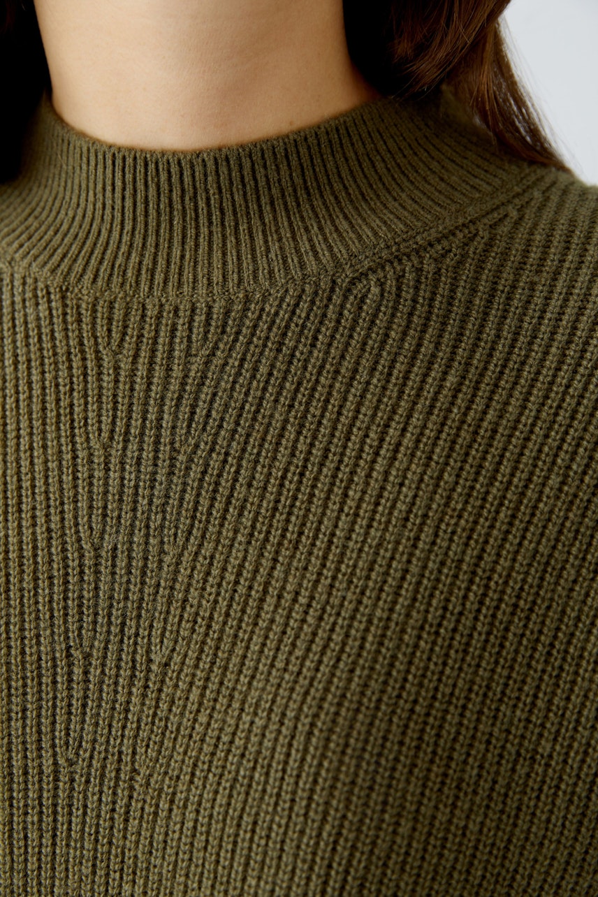 Damen-Pullover in Olivgrün: Frau trägt einen lässigen, gerippten Pullover mit hohem Kragen.