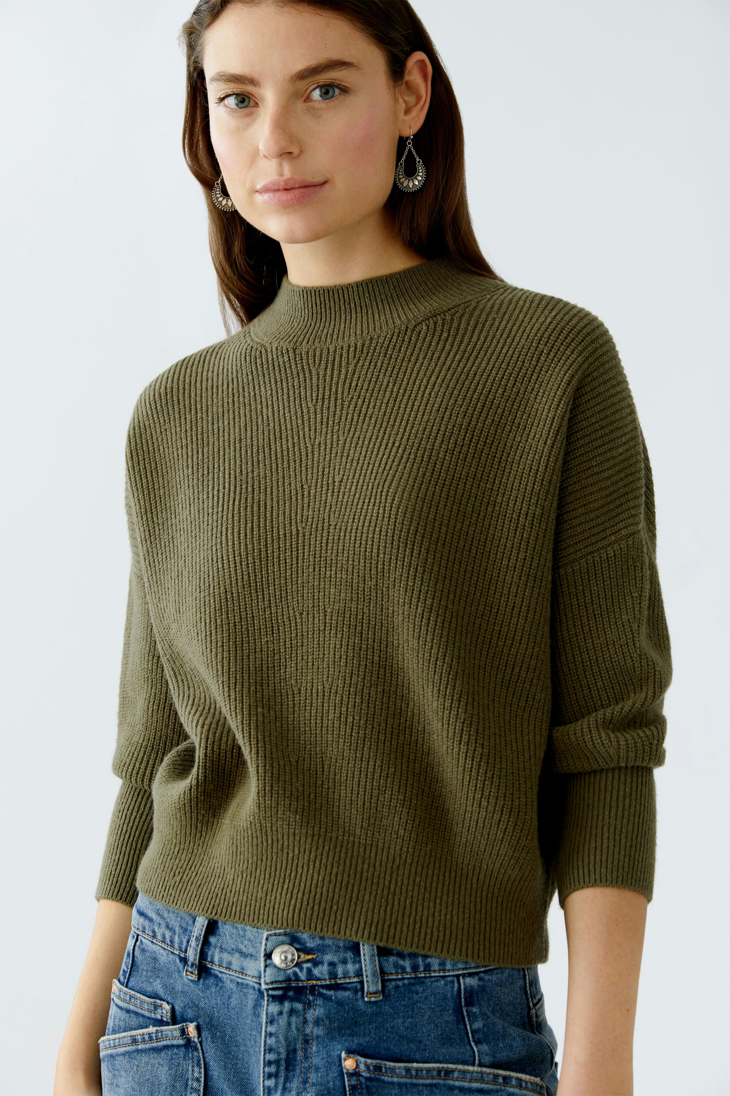 Casual women's pullover: A woman in a green ribbed pullover paired with denim jeans.