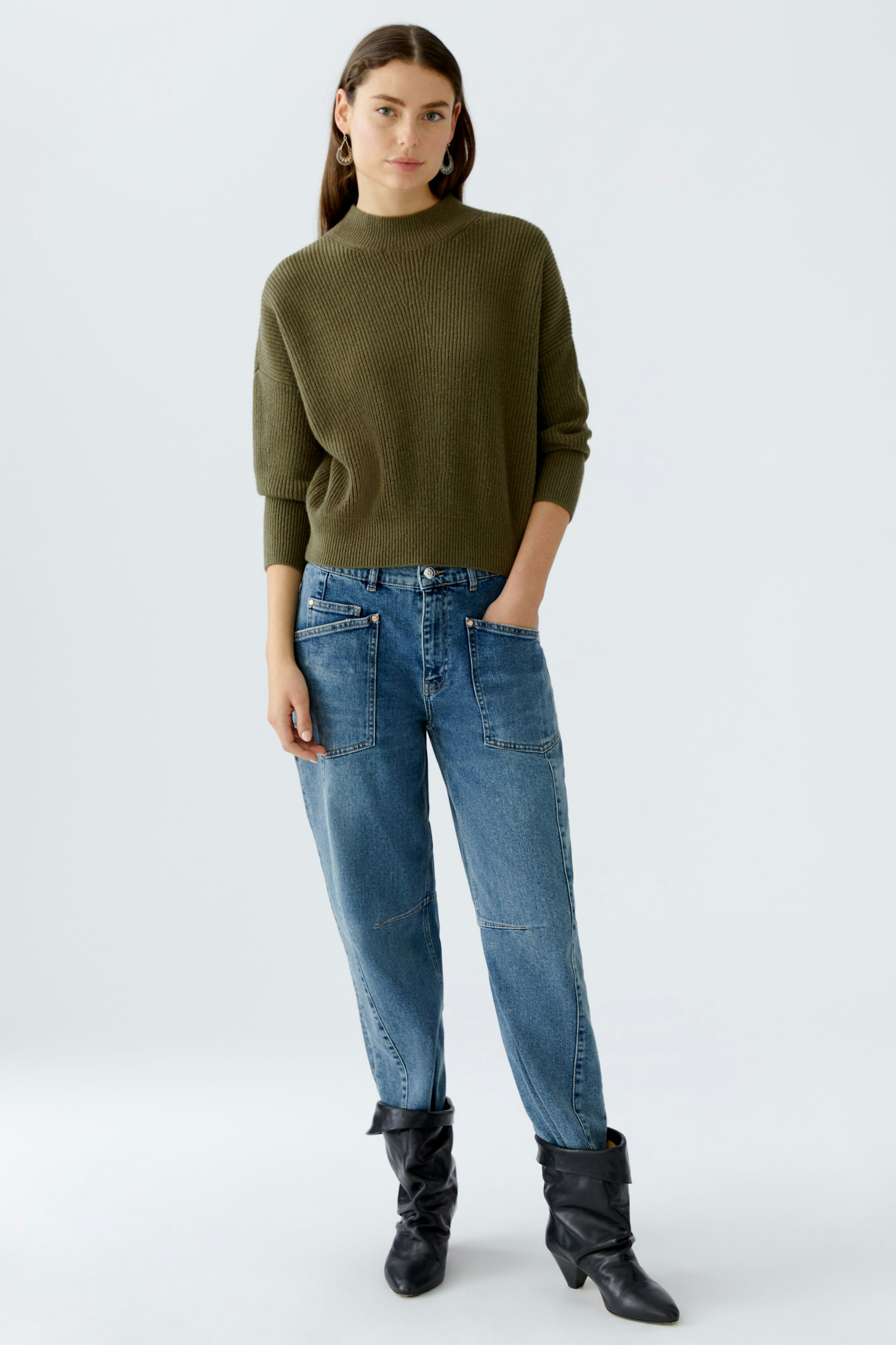Casual women's pullover: Young woman in a green pullover paired with relaxed-fit jeans.