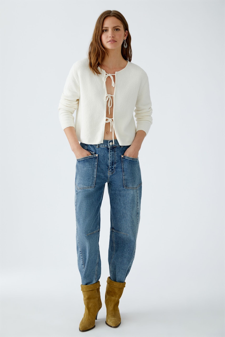 Casual women's cardigan: A woman in a white cardigan with a tie front, paired with relaxed jeans.