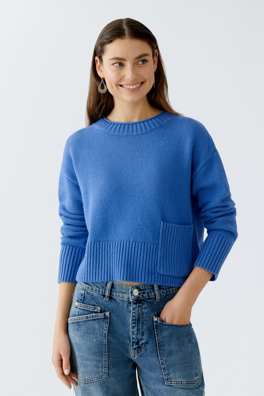 Casual women's pullover: Young woman in a blue pullover with a pocket, paired with relaxed jeans.
