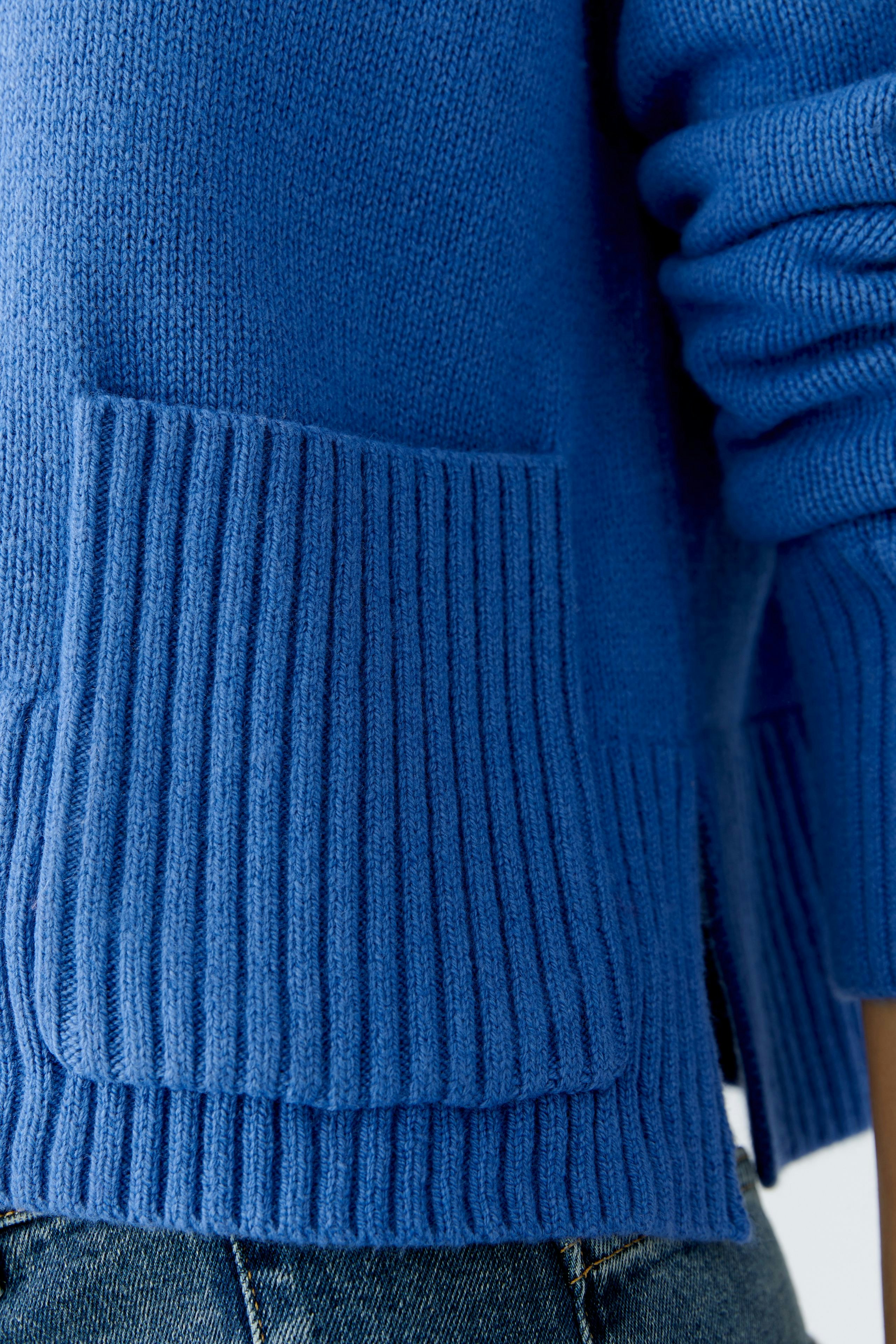 Casual women's pullover: Close-up of a blue knit pullover with ribbed cuffs and pockets.