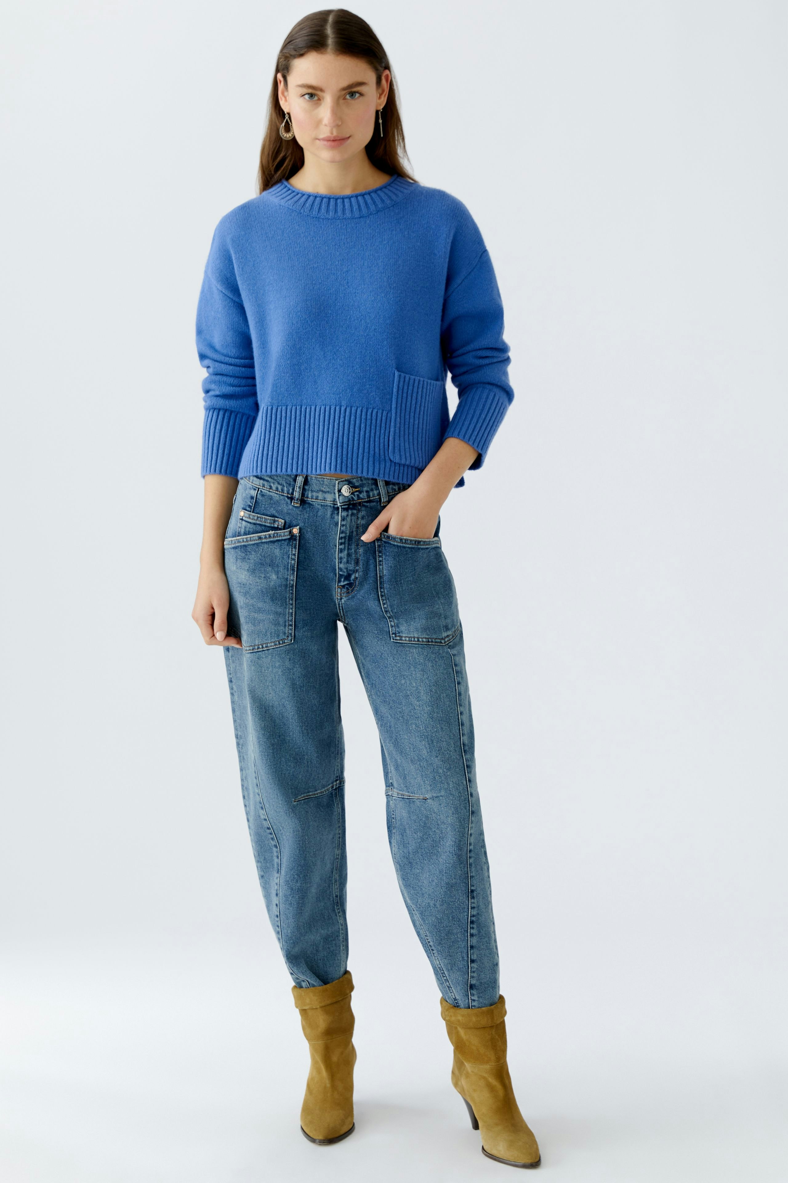 Casual women's pullover: Young woman in a blue knitted pullover with a relaxed fit and jeans.