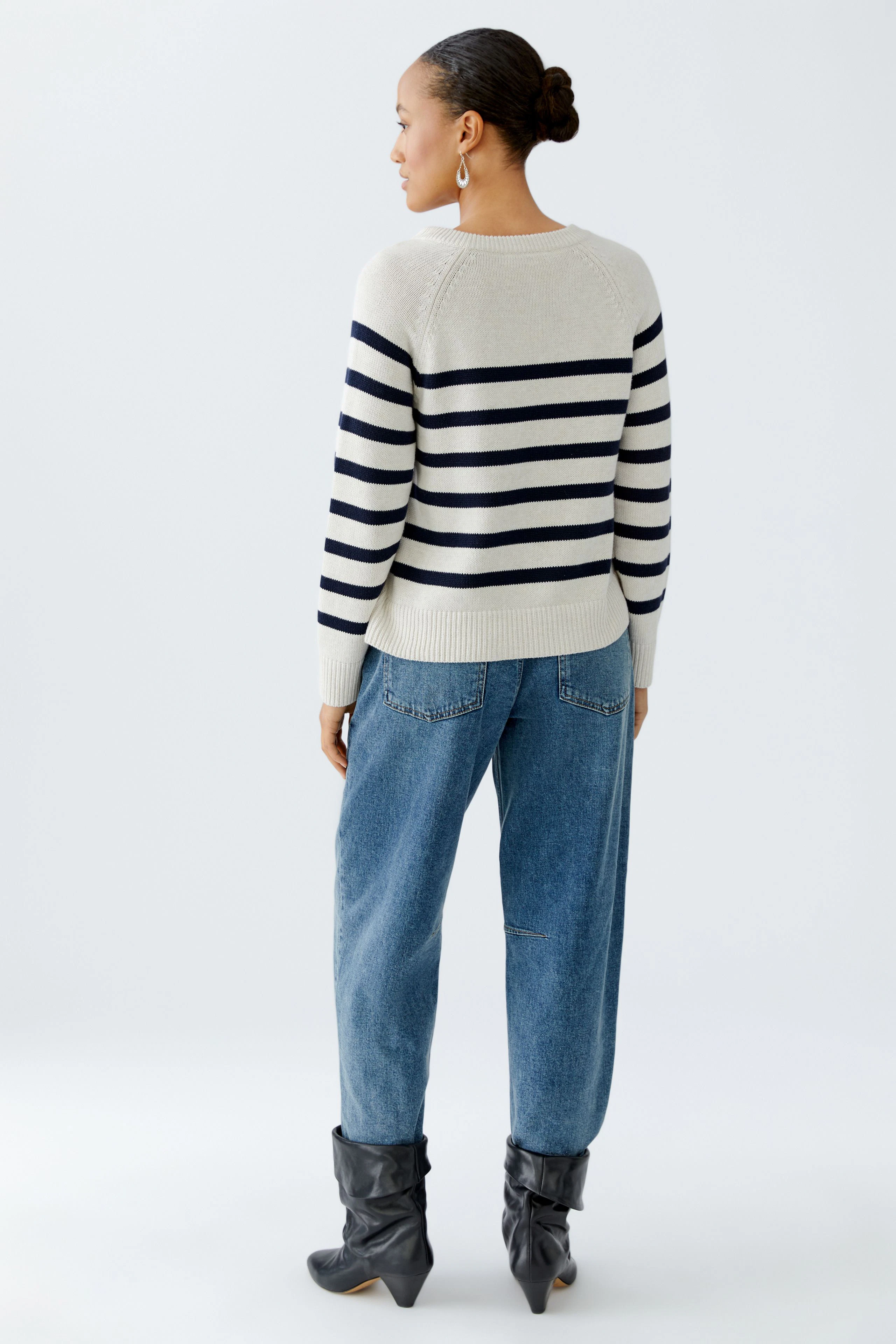 Damen-Pullover: Frau trägt einen gestreiften Pullover in Beige und Marineblau, kombiniert mit lässigen Jeans.