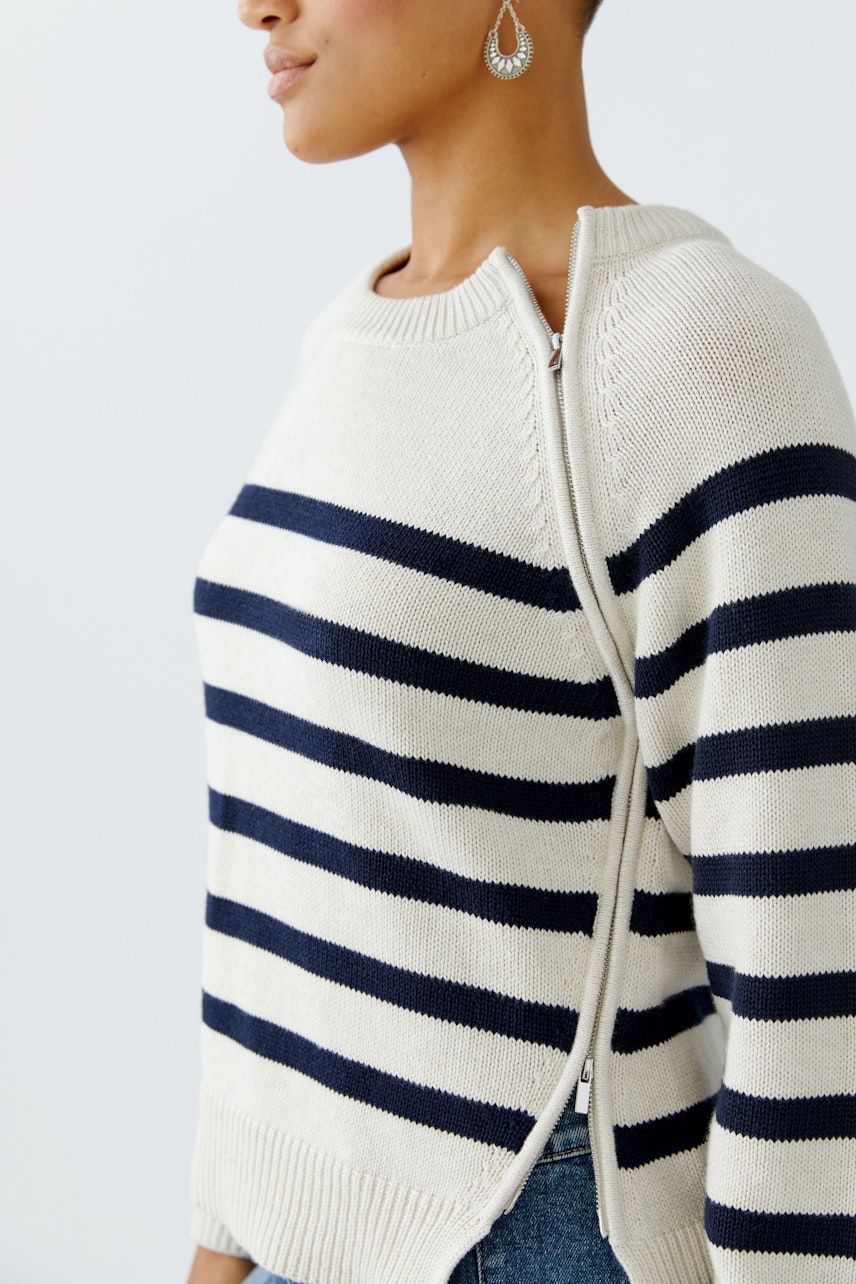 Damen-Pullover: Frau in gestreiftem Pullover mit Reißverschluss und lässigem Look.