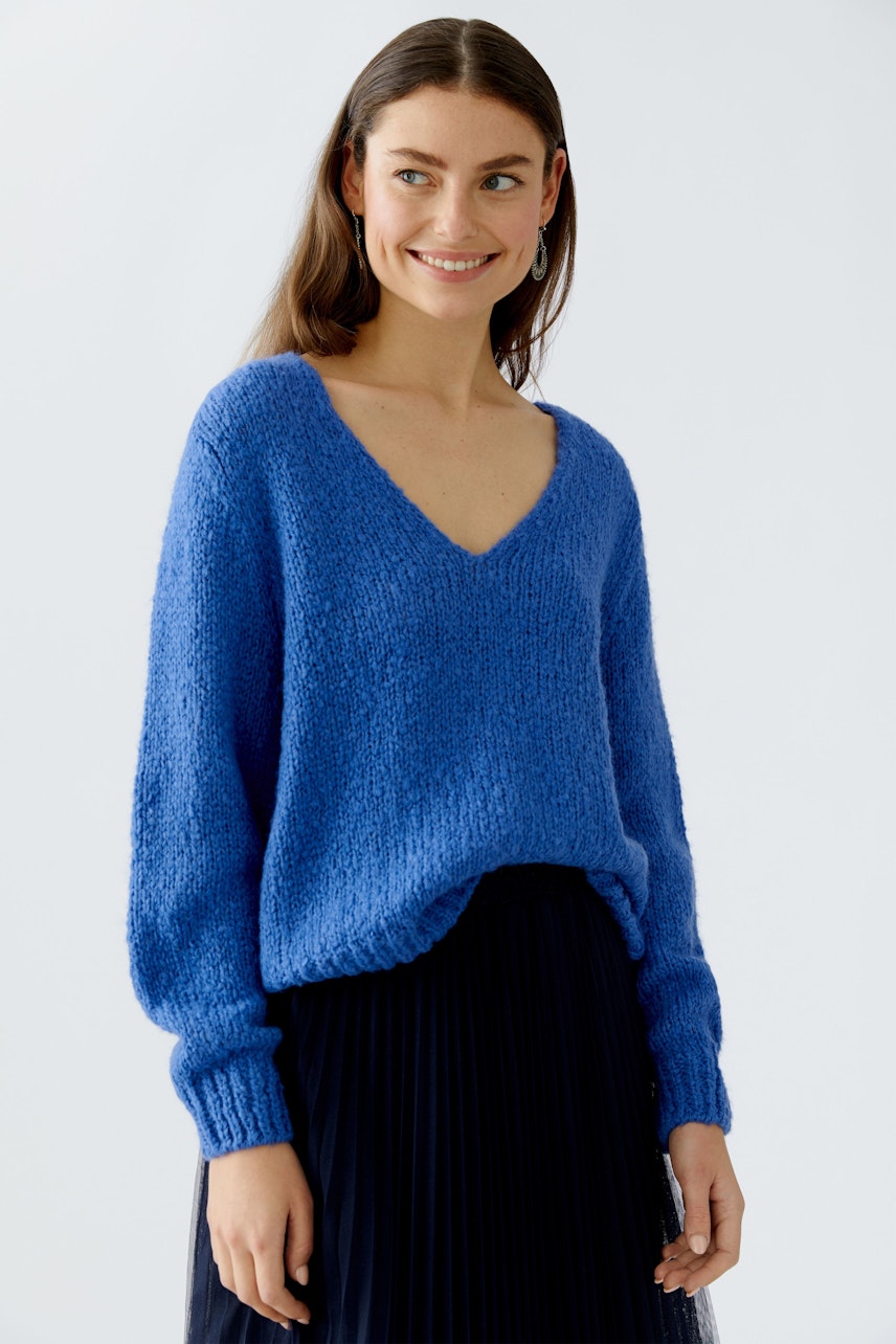 Bequemer Damen-Pullover in Blau mit V-Ausschnitt, lässig kombiniert mit einem plissierten Rock.