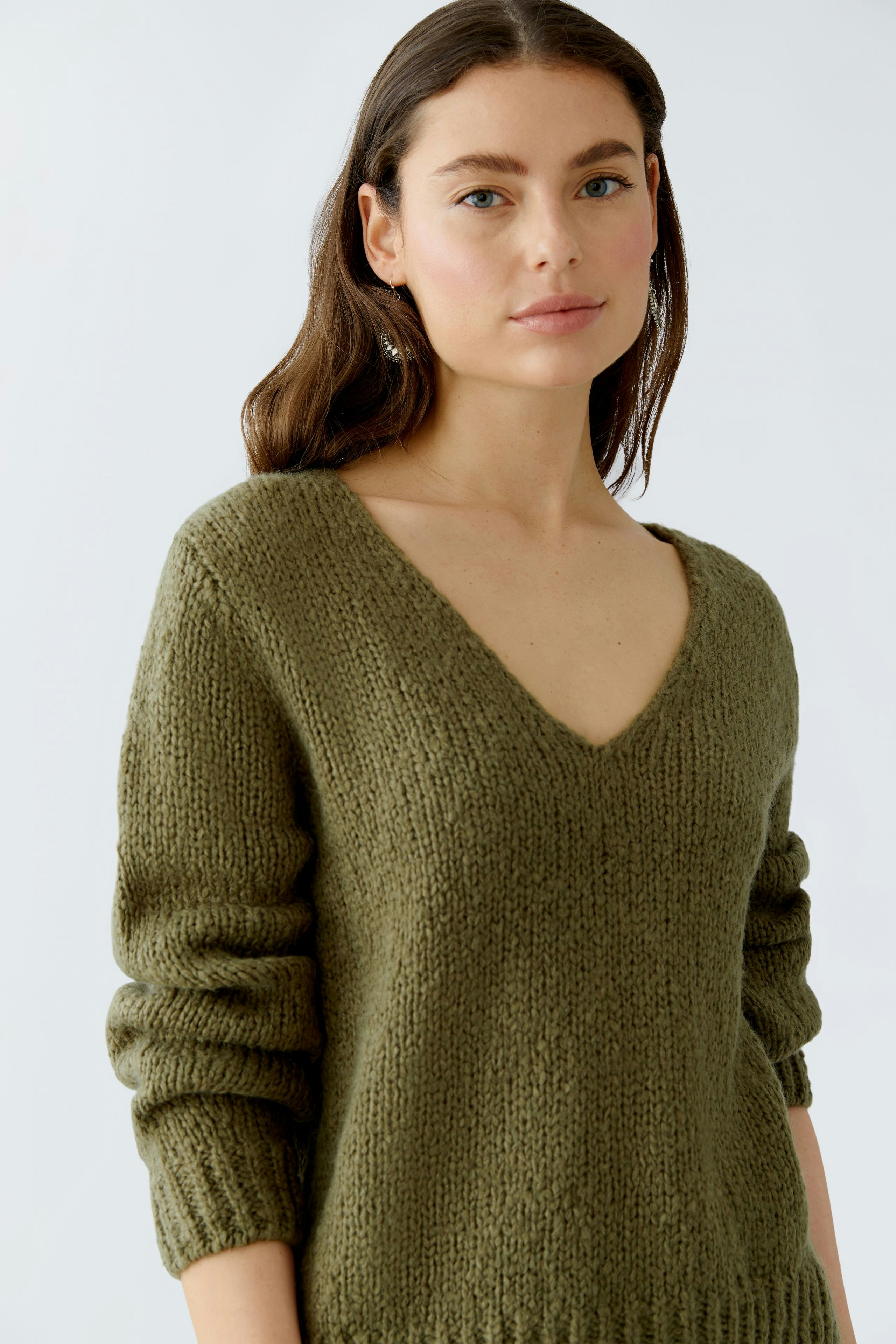 Casual women's pullover: A woman in a cozy green V-neck pullover with relaxed sleeves.