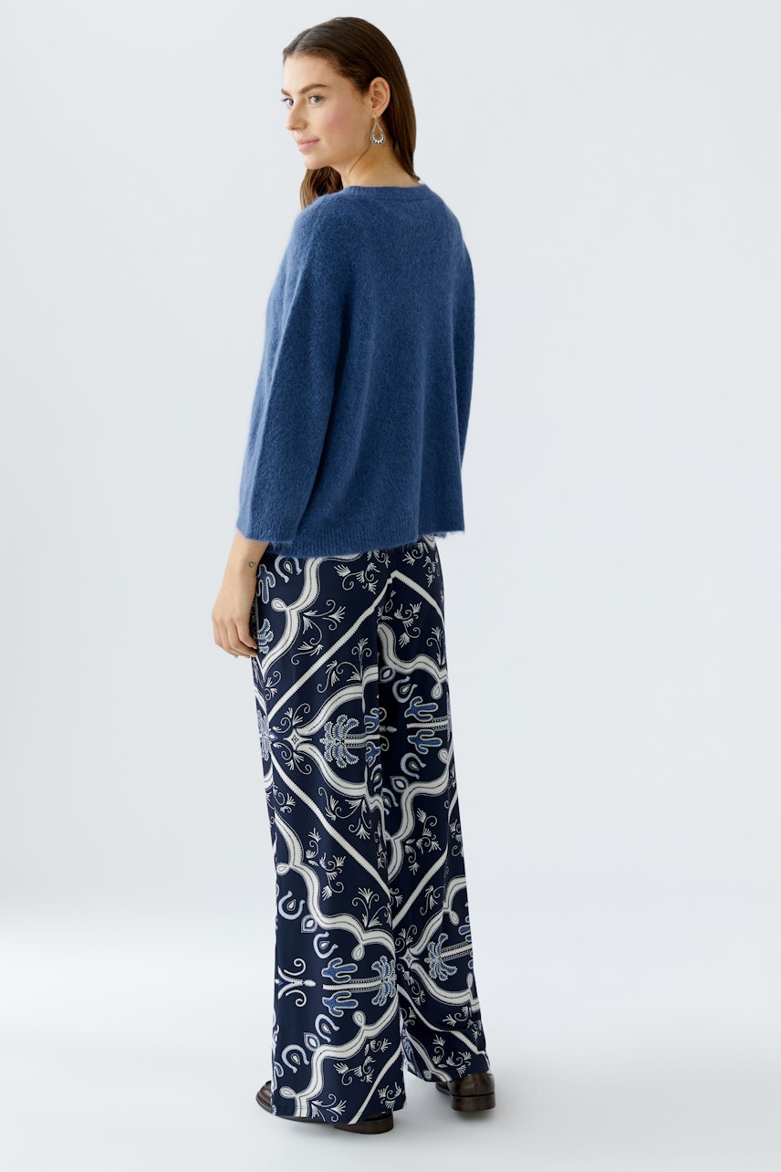 Damen-Pullover: Frau in blauem, lässigem Strickpullover mit weitem Schnitt und gemusterter Hose.