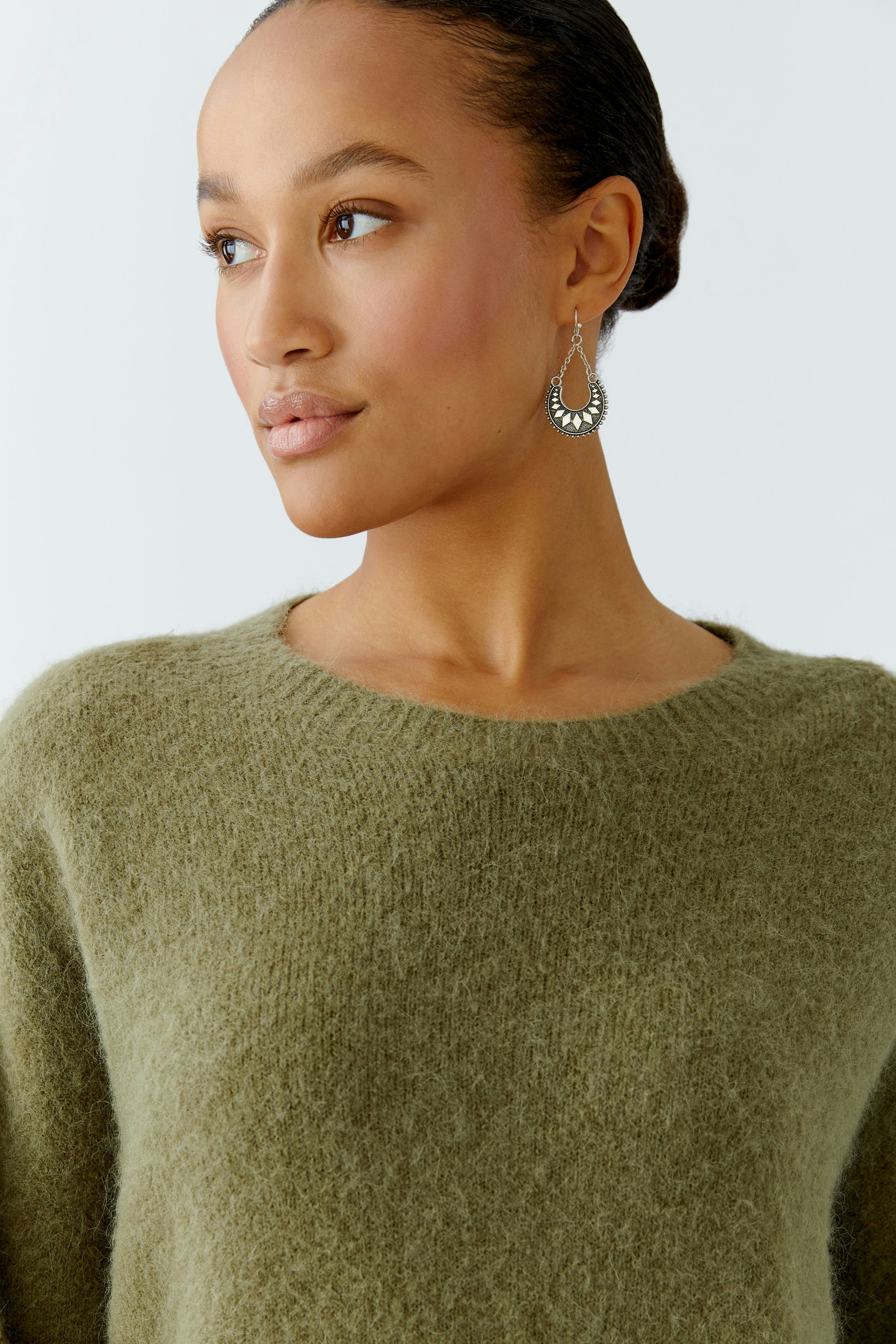 Damen-Pullover in sanftem Olivgrün: Frau mit lässigem Look und weichem Material.