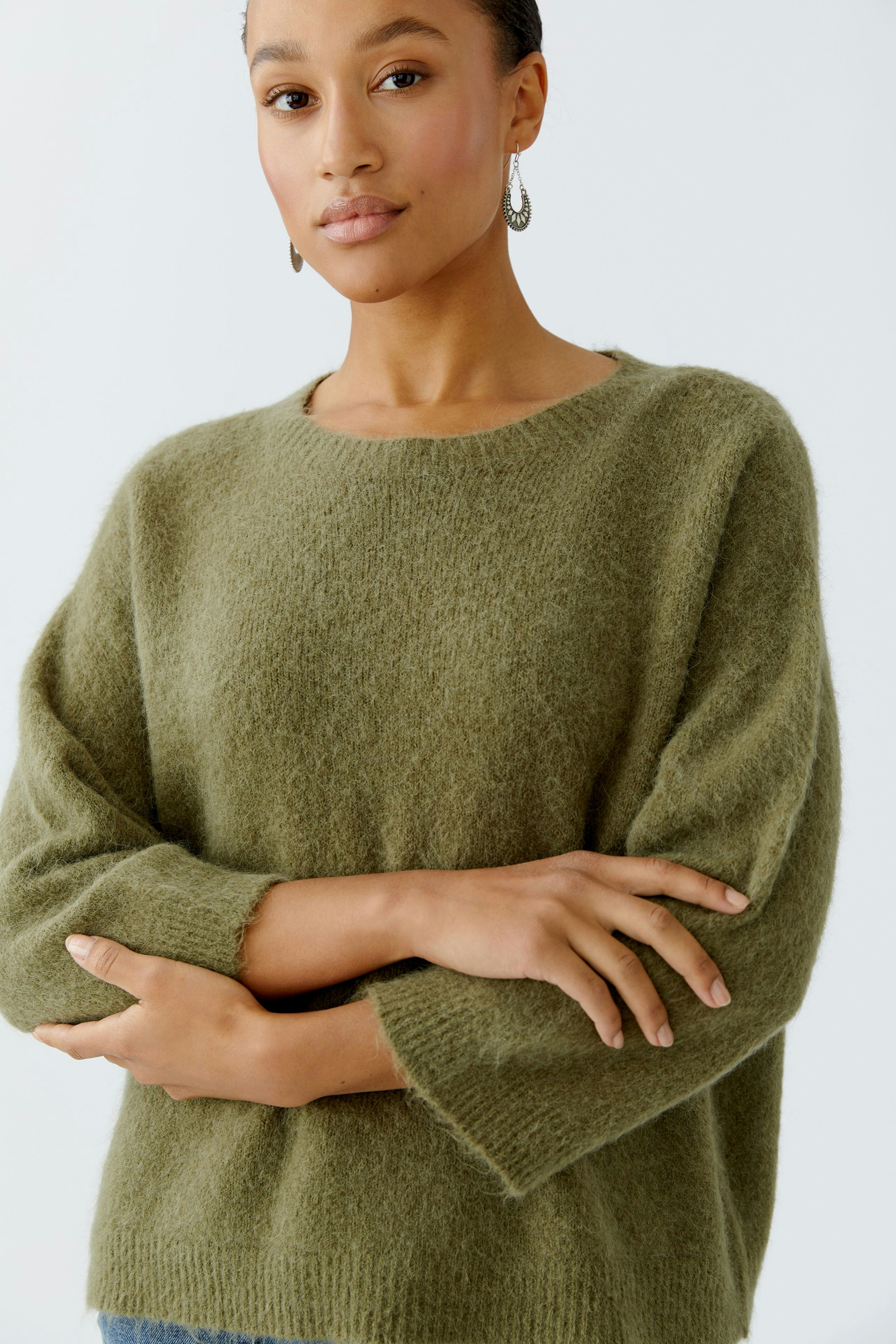 Damen-Pullover in sanftem Olivgrün: Frau trägt einen lässigen, weichen Strickpullover mit weitem Schnitt.