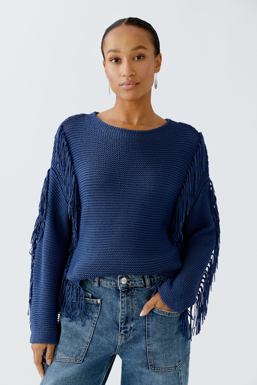 Damen-Pullover in Blau mit Fransen: Frau trägt lässigen Pullover zu Jeans und strahlt Selbstbewusstsein aus.