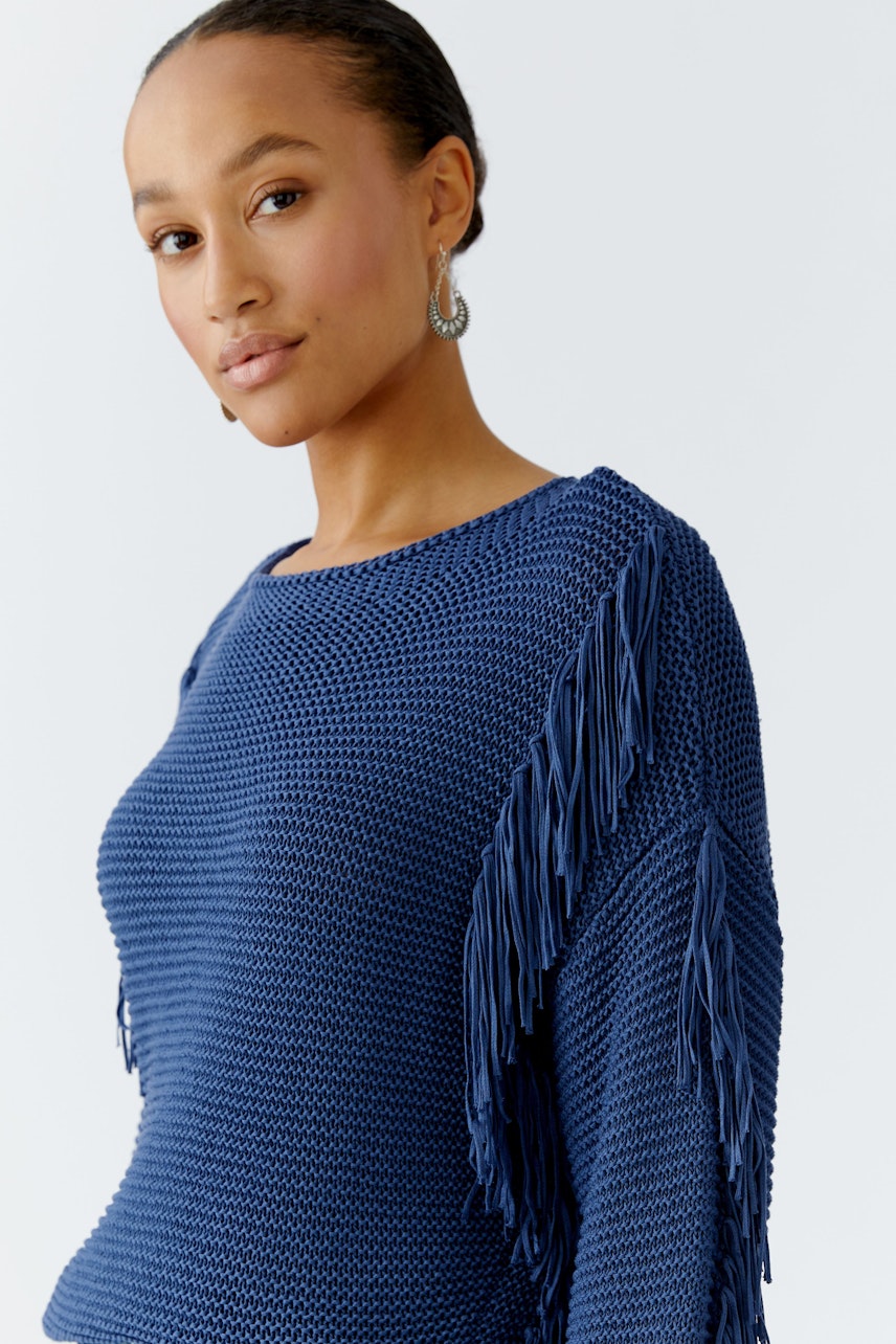 Damen-Pullover in Blau mit Fransen, lässig und modern, getragen von einer Frau.